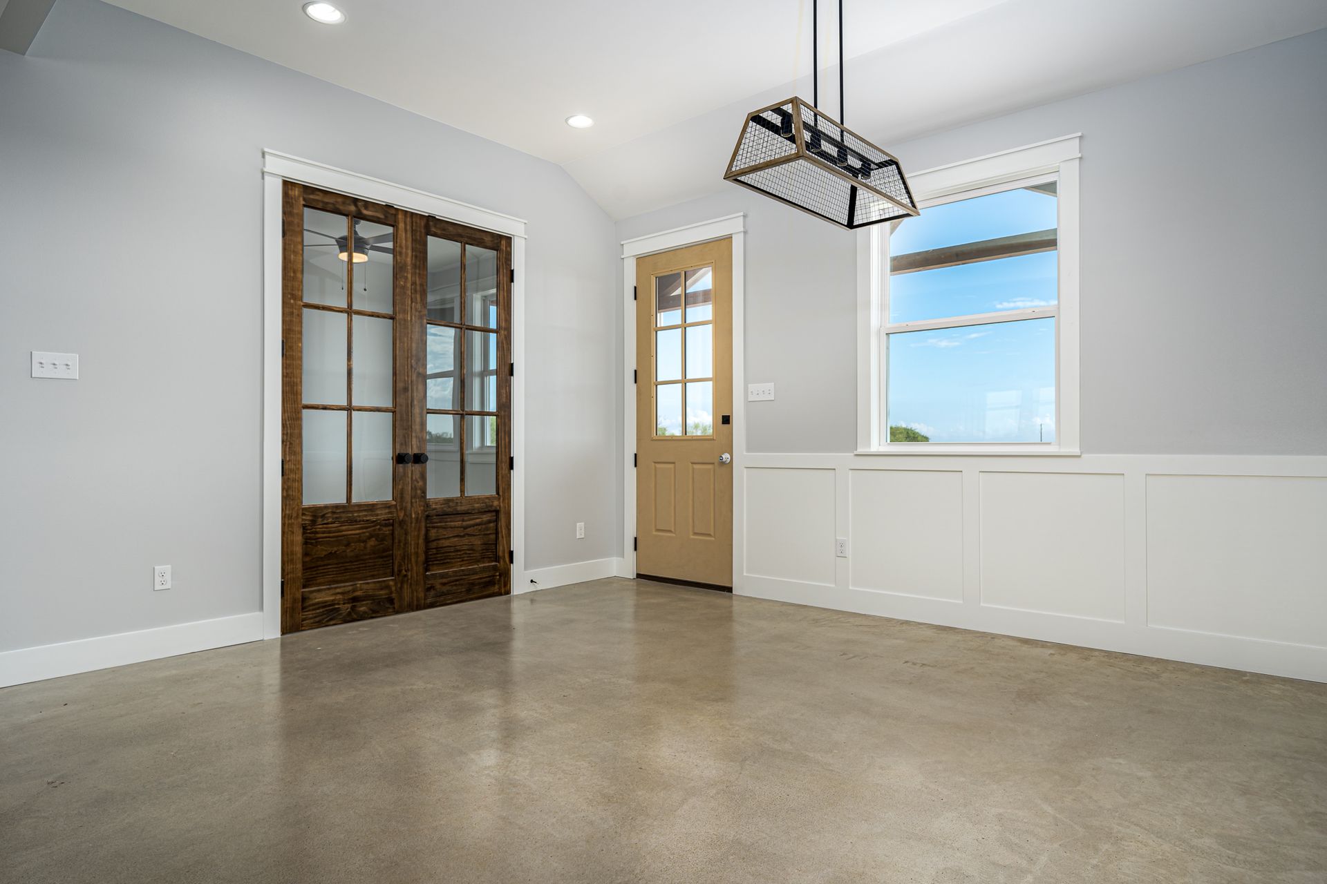 An empty room with a wooden door and a window.