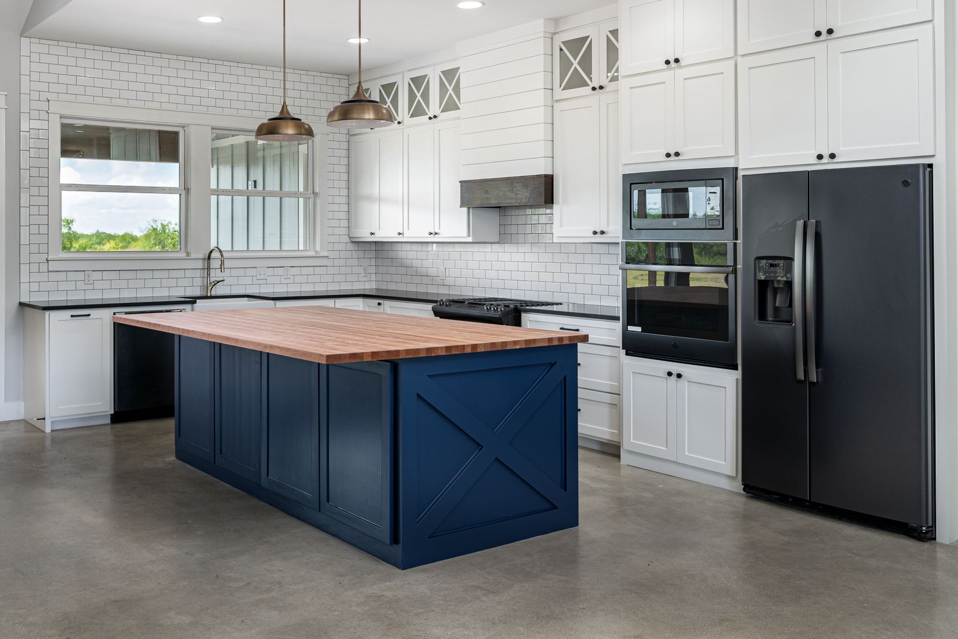 A kitchen with white cabinets , black appliances , and a large blue island.
