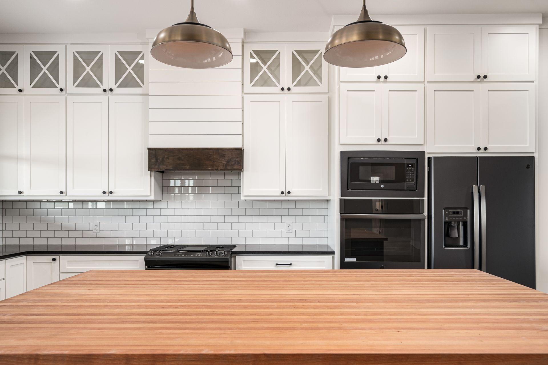 There is a wooden table in the middle of the kitchen.