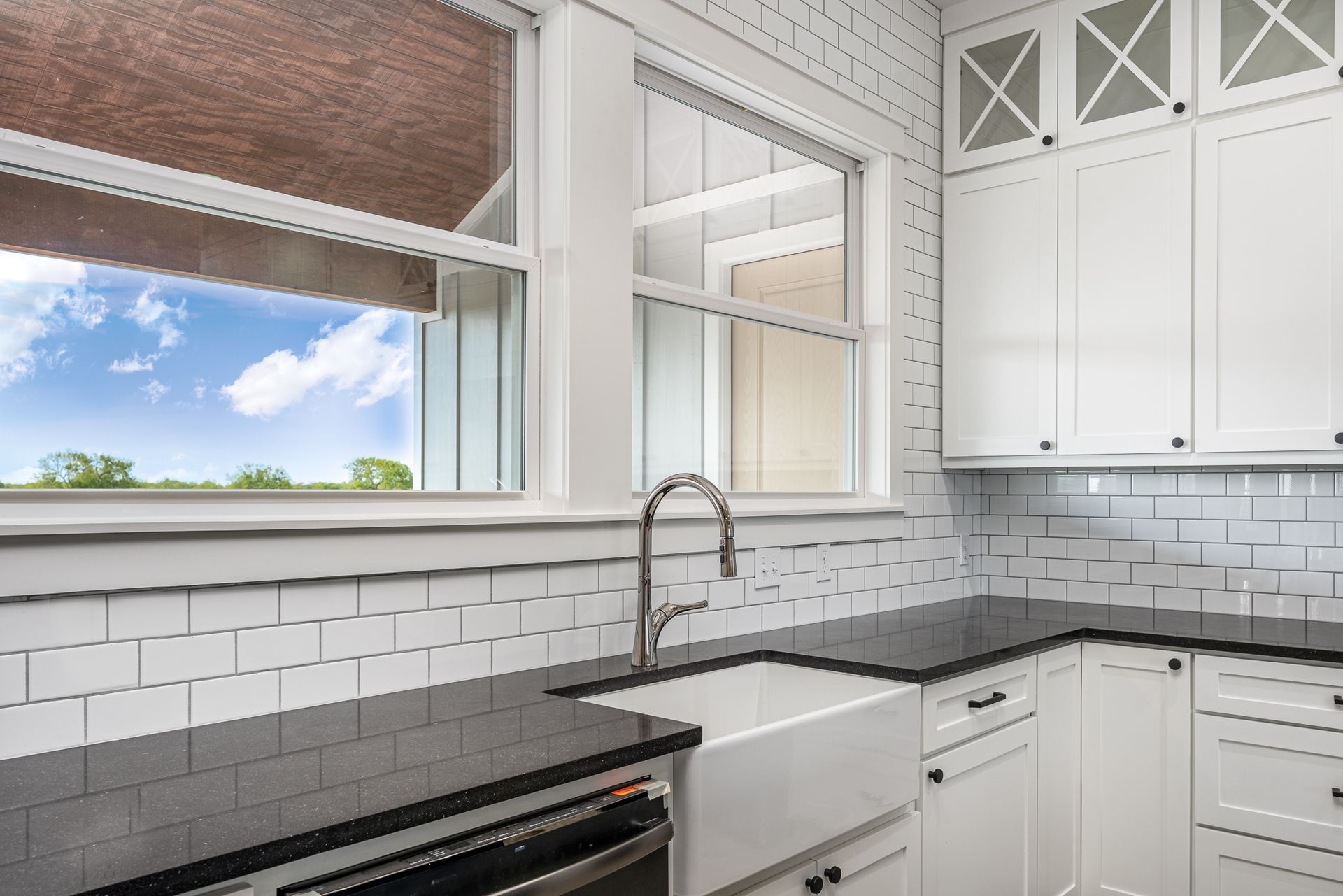 A kitchen with white cabinets and black counter tops