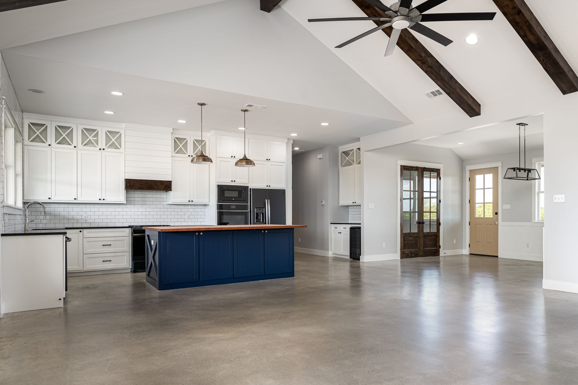 A large empty kitchen with a blue island and a ceiling fan.