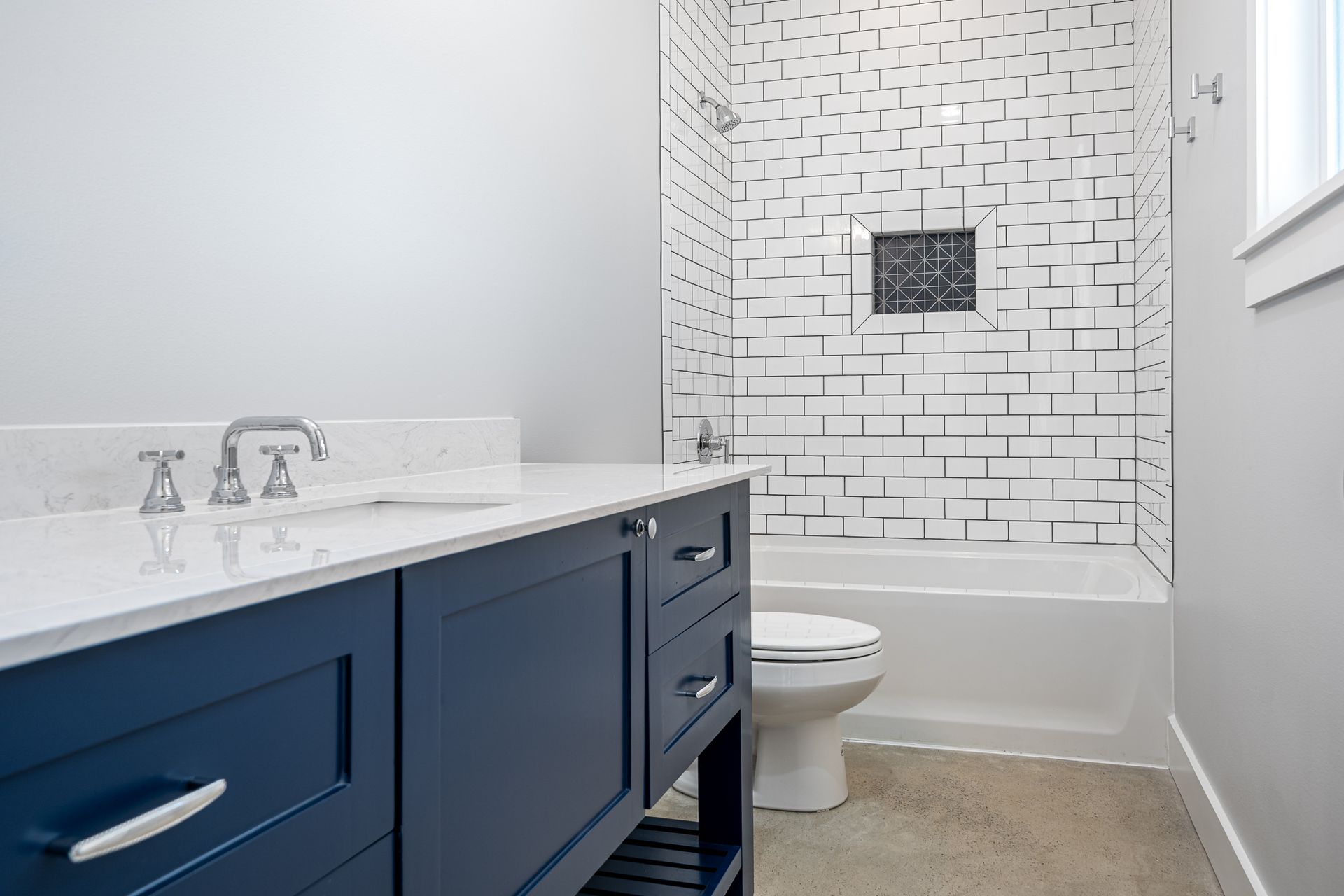 A bathroom with a blue vanity , toilet , and bathtub.