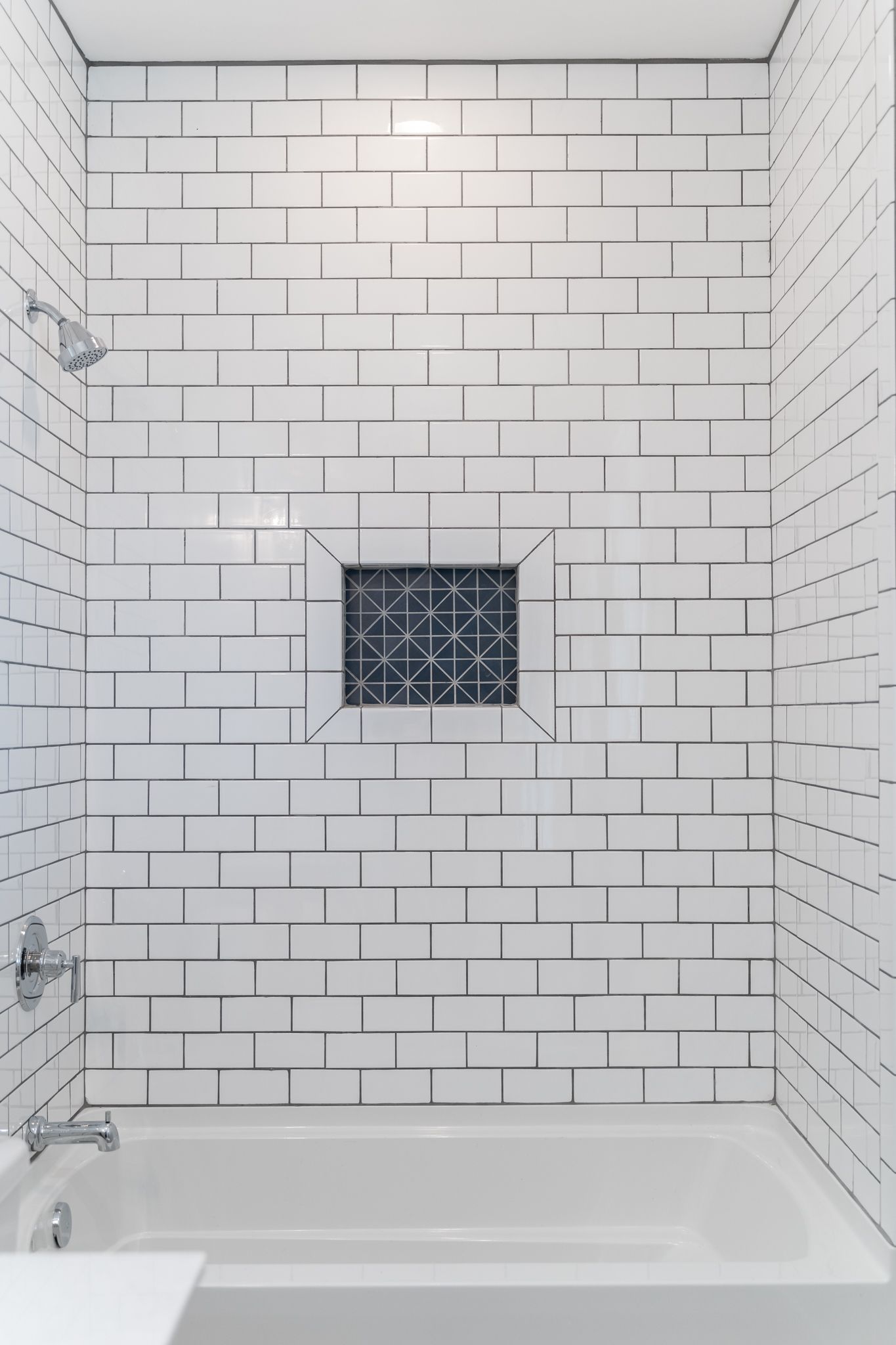 A bathroom with black and white tiles and a bathtub