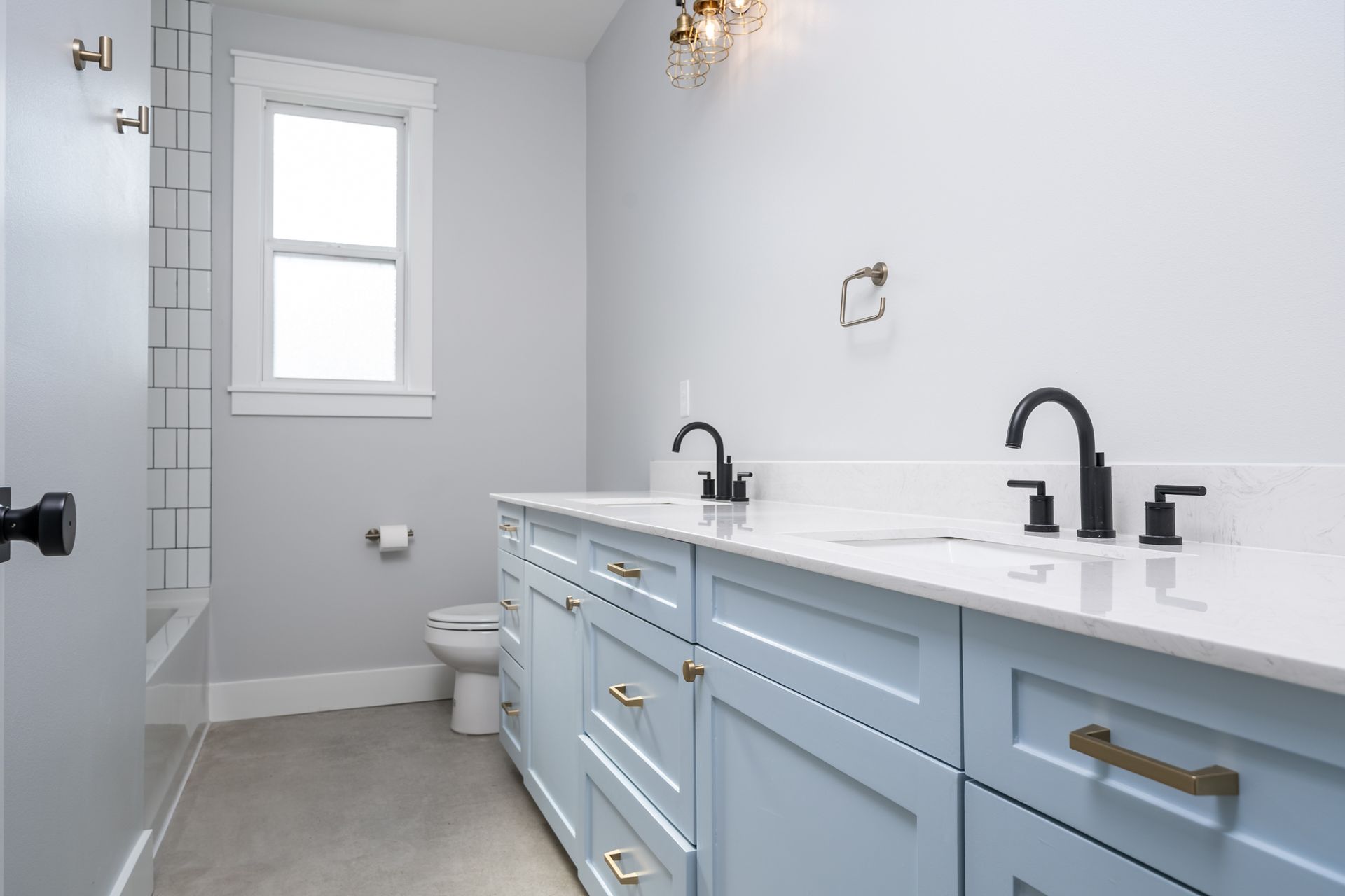 A bathroom with two sinks , a toilet , and a window.