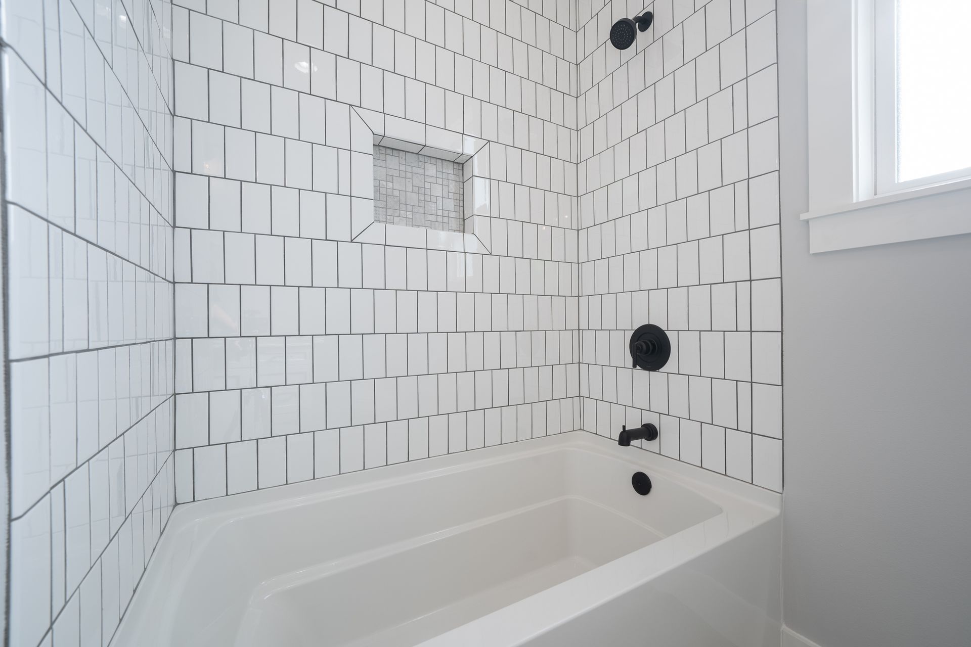 A bathroom with white tiles and a bathtub