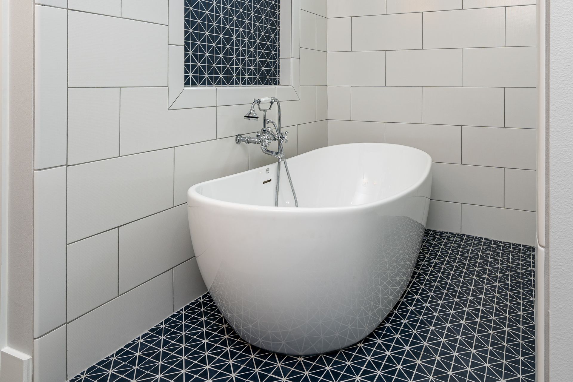 A white bathtub in a bathroom with black and white tiles