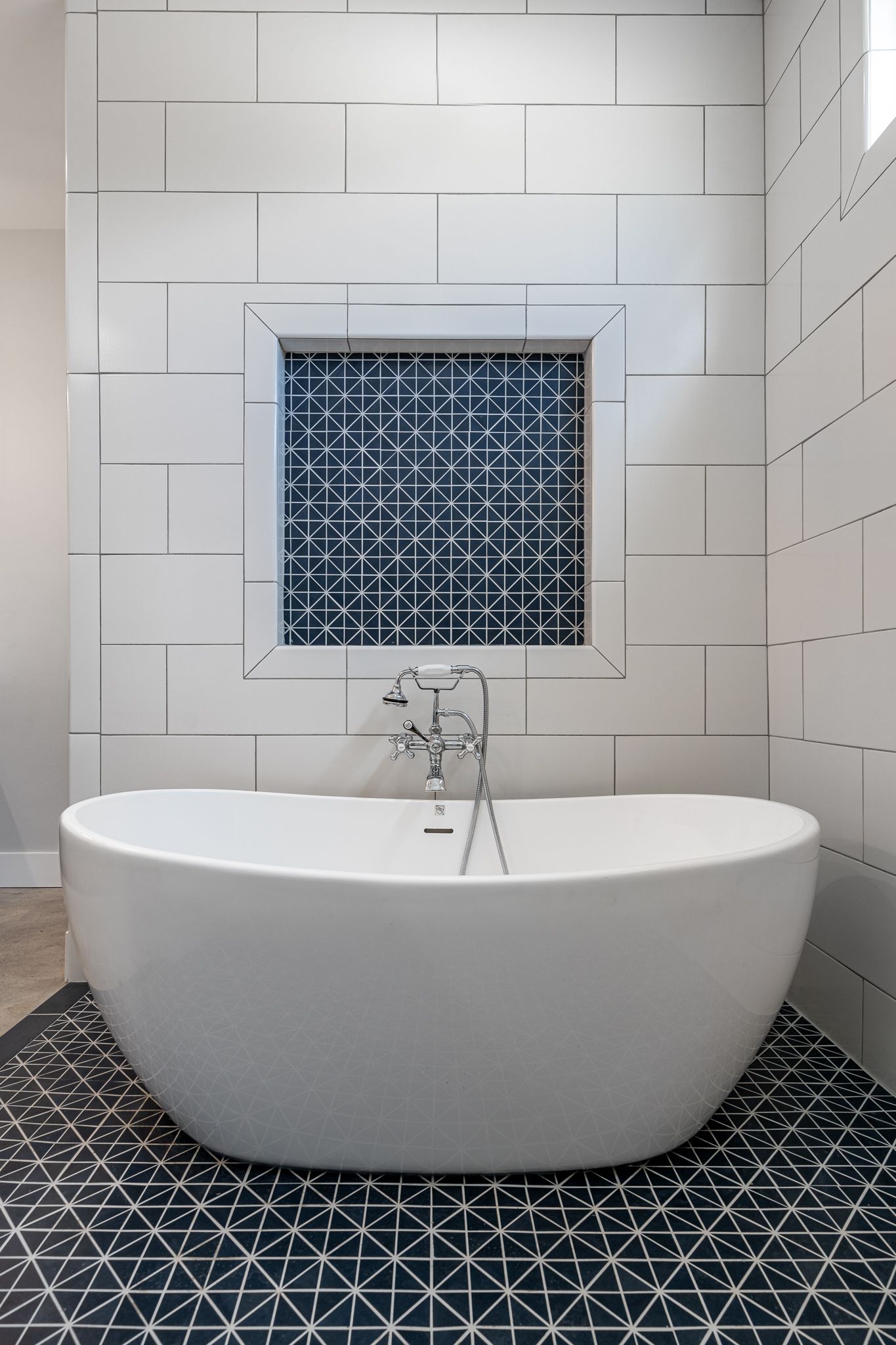 A white bathtub is sitting in a bathroom next to a window.
