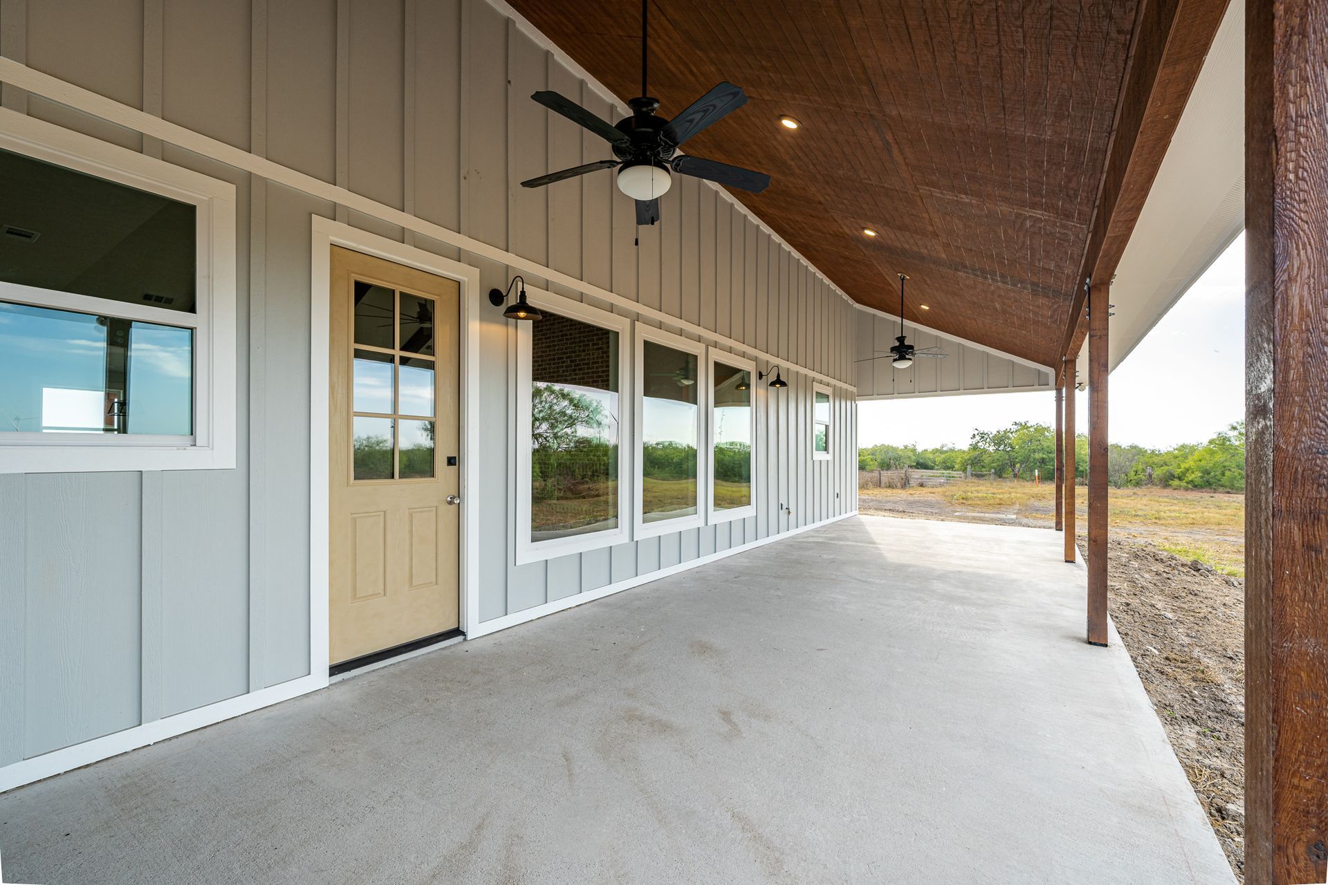 A large porch with a ceiling fan and a lot of windows