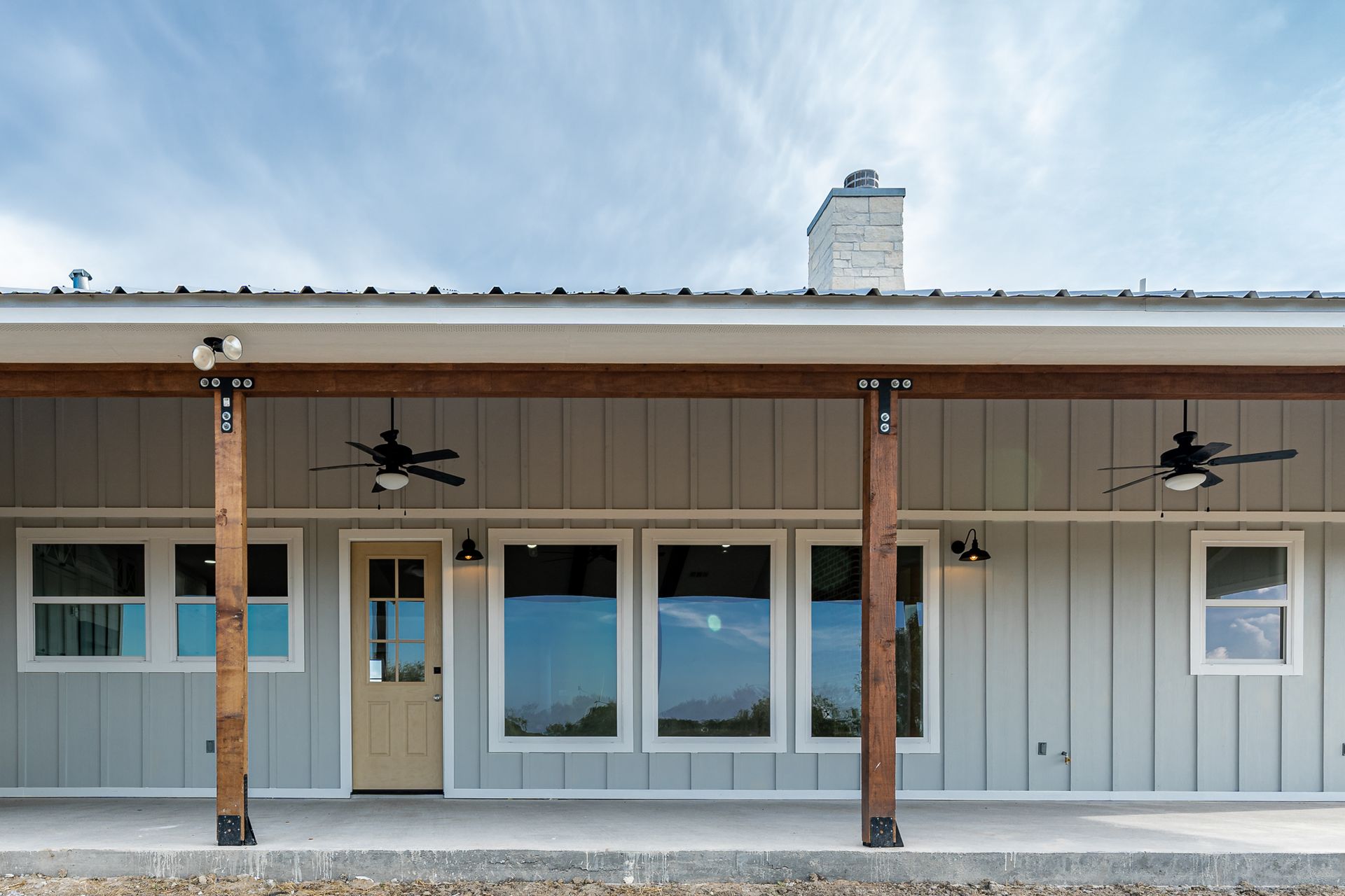 The front of a house with a porch and ceiling fans.