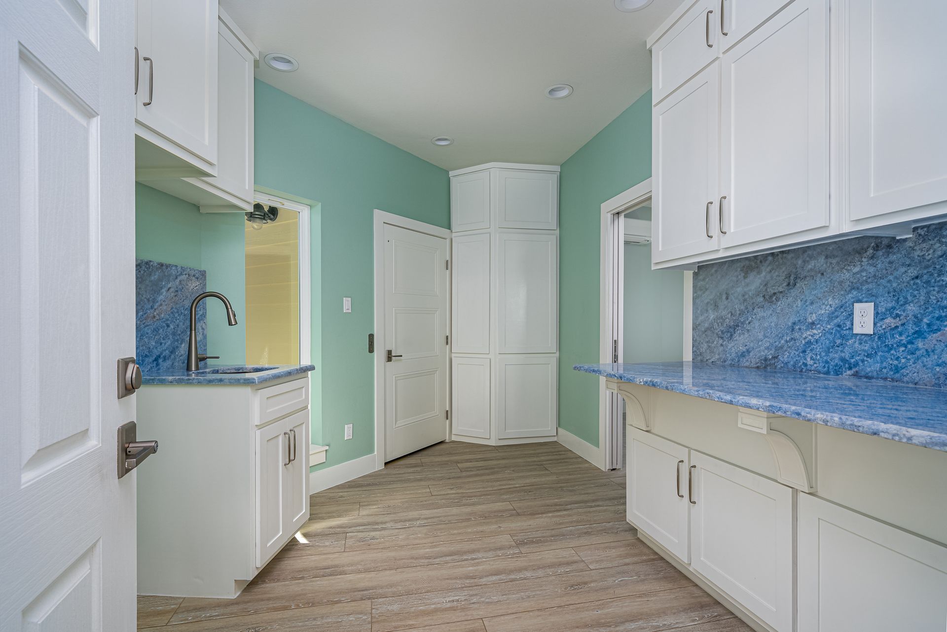 A kitchen with white cabinets and blue counter tops.