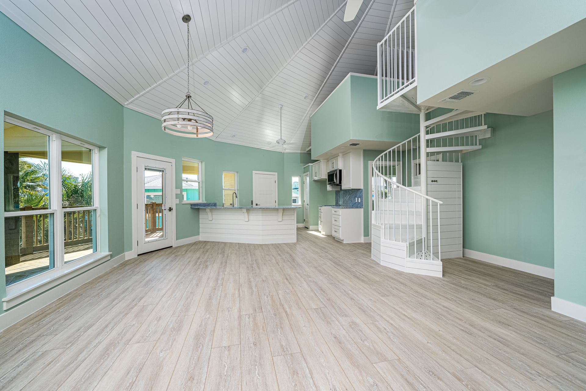 A large empty room with a spiral staircase leading to the second floor.