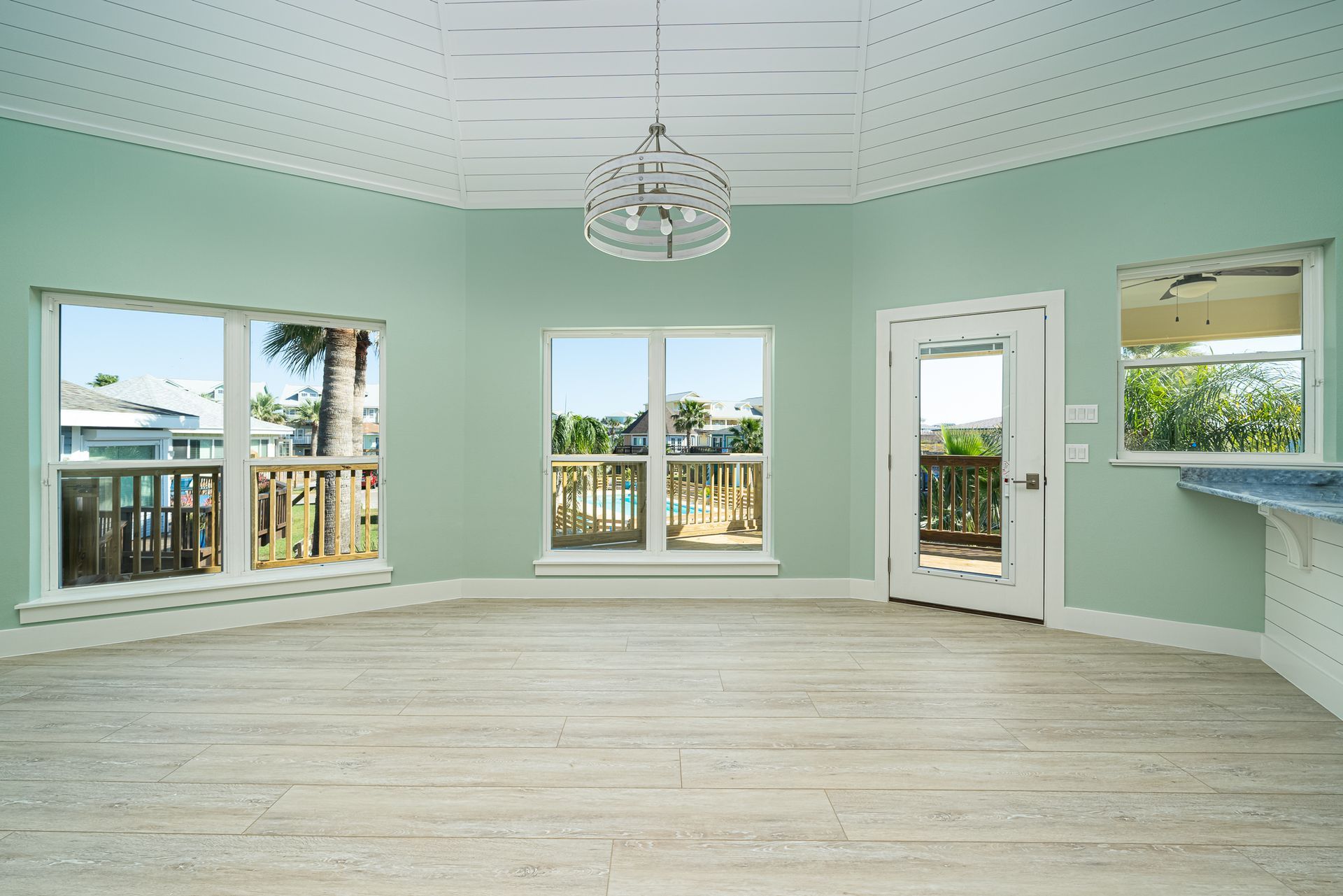 An empty room with lots of windows and a chandelier