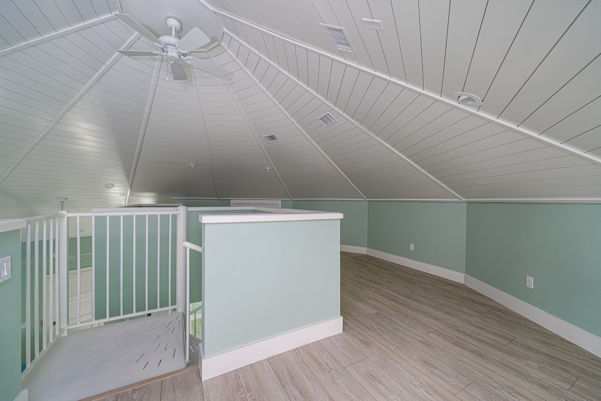 There is a ceiling fan in the attic of a house.