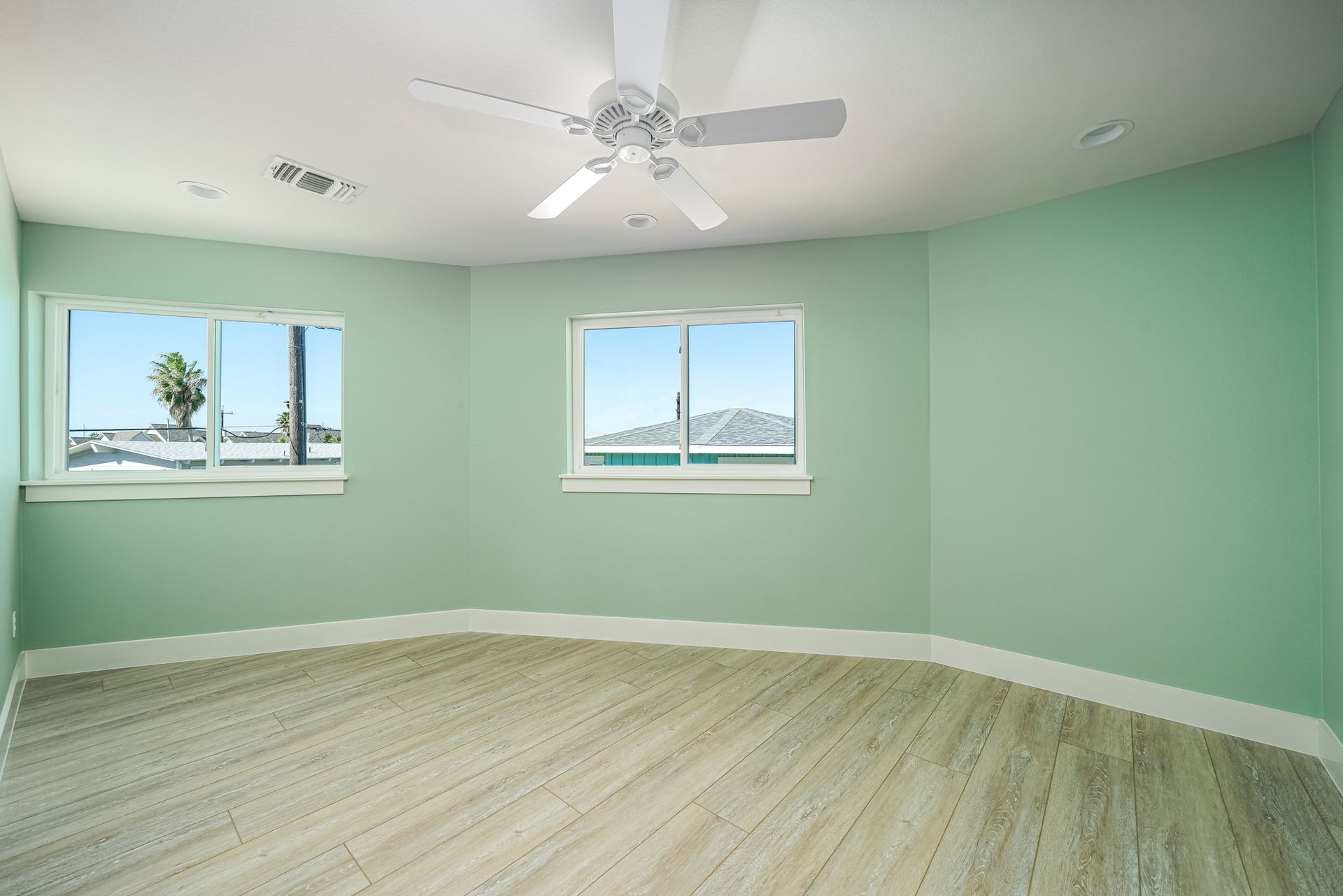An empty room with a ceiling fan and three windows