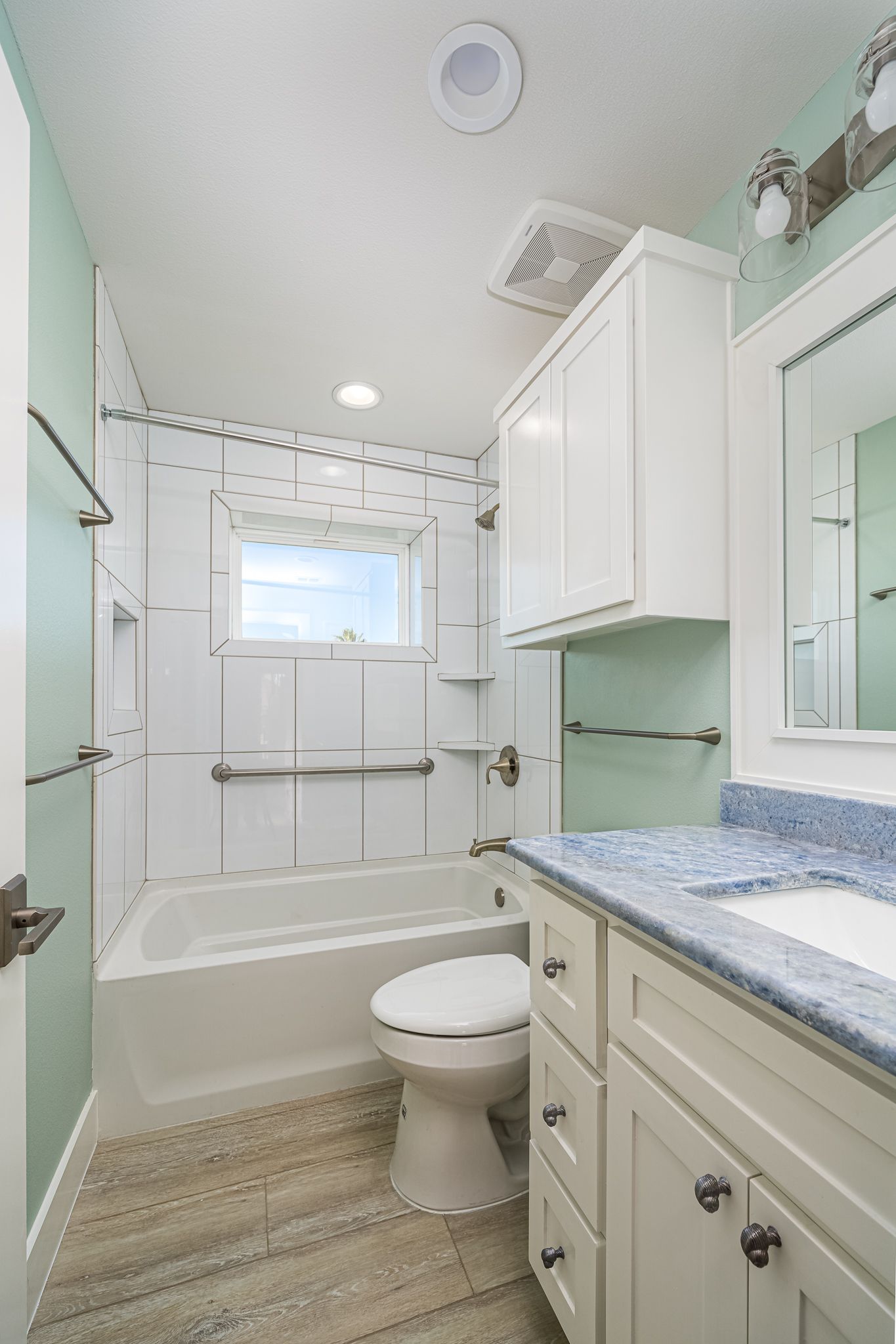 A bathroom with a toilet , sink , tub and mirror.