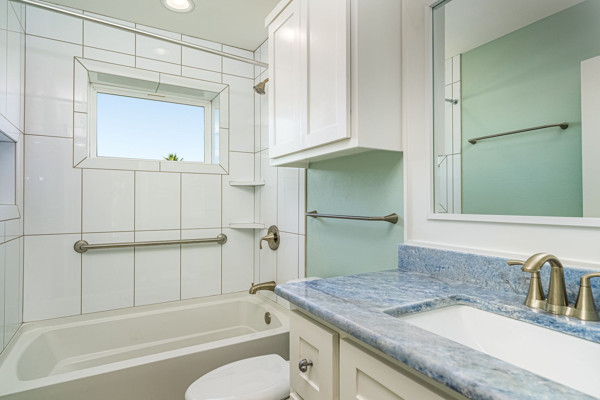 A bathroom with a sink , toilet , tub and window.