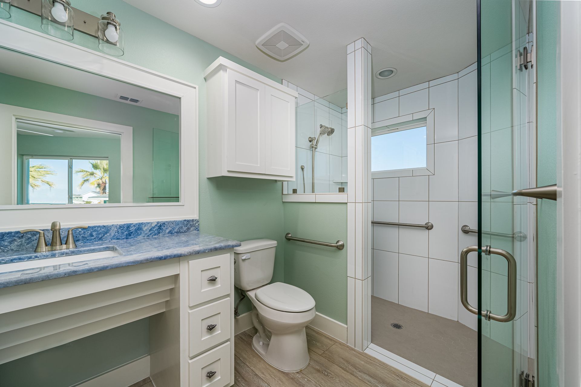A bathroom with a toilet , sink , mirror and walk in shower.