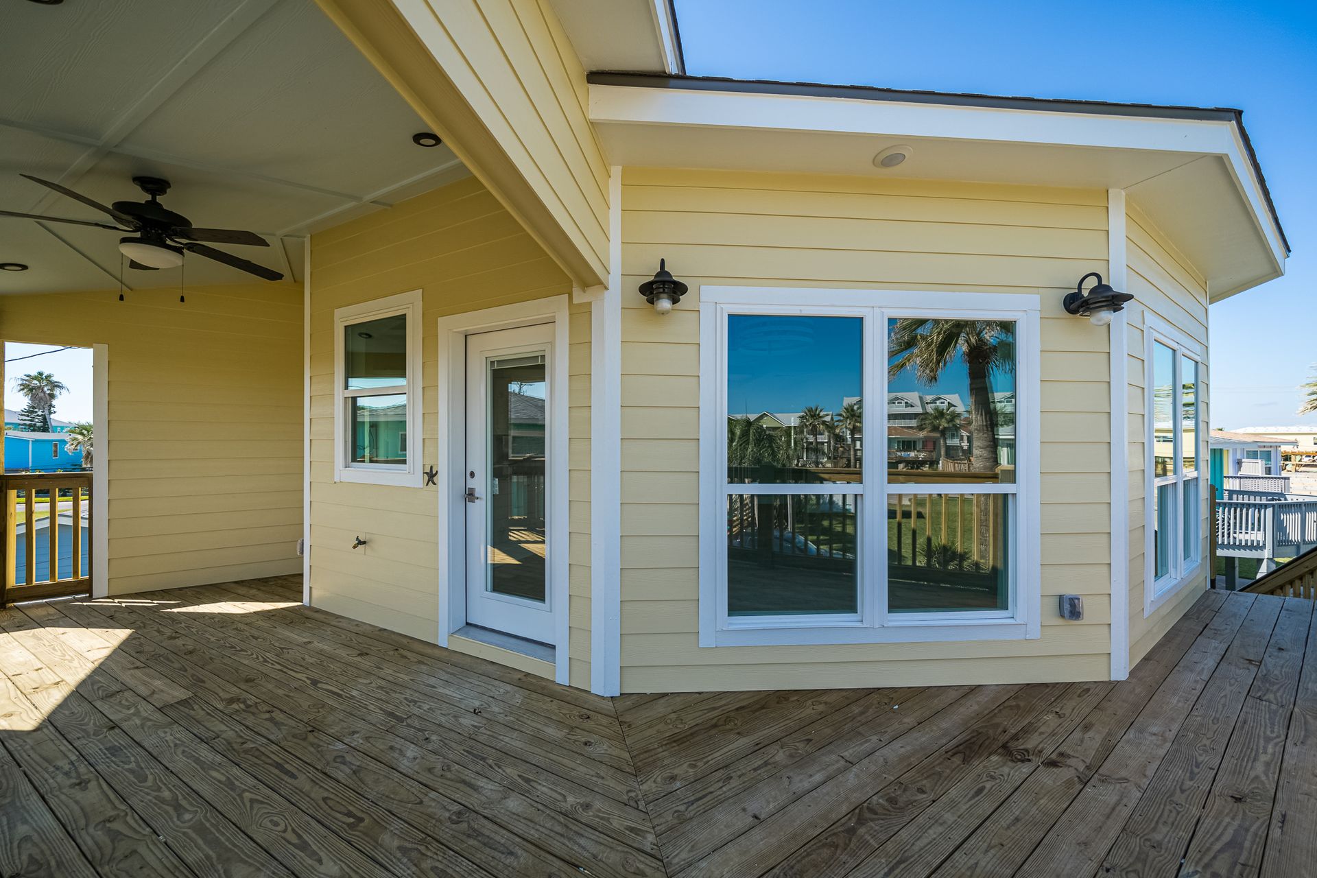 A yellow house with a deck and a ceiling fan