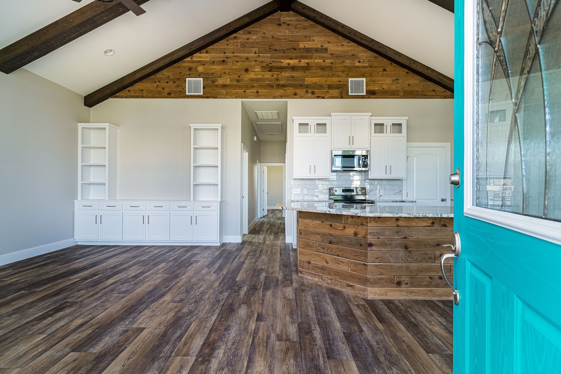 A living room with a blue door and a kitchen in the background.