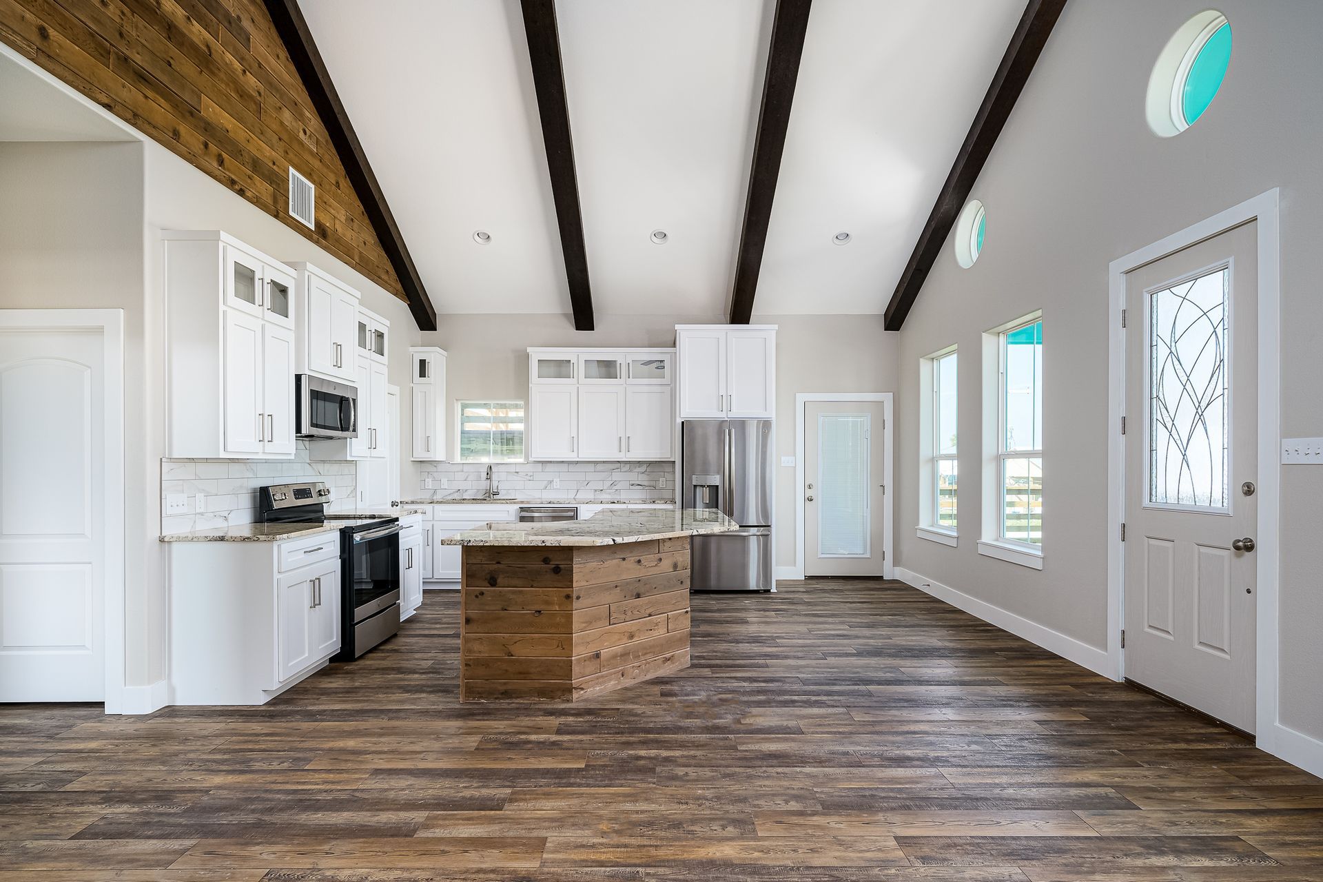 A kitchen with white cabinets , stainless steel appliances , and wooden floors.