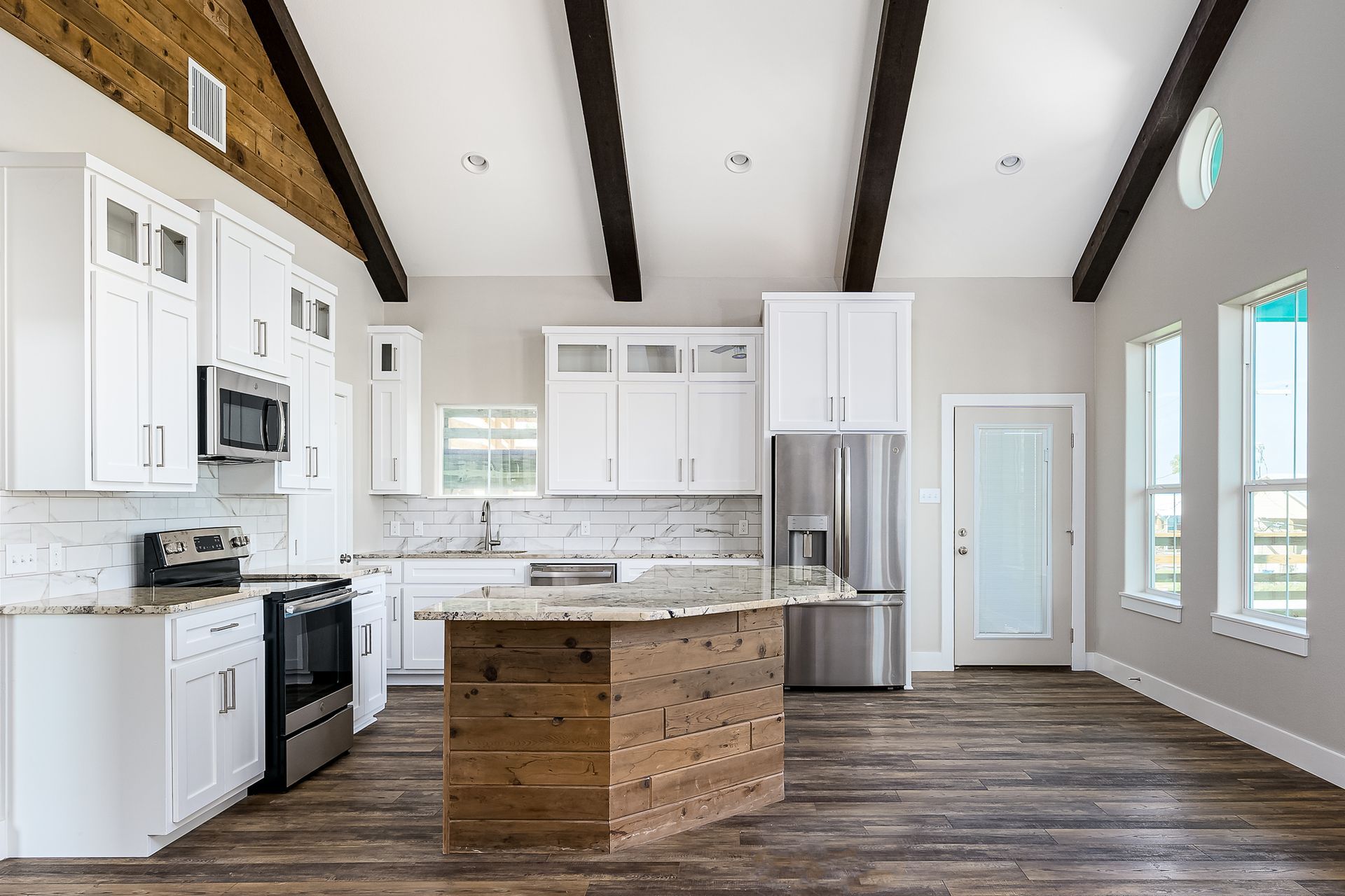 A kitchen with white cabinets , stainless steel appliances , and a wooden island.