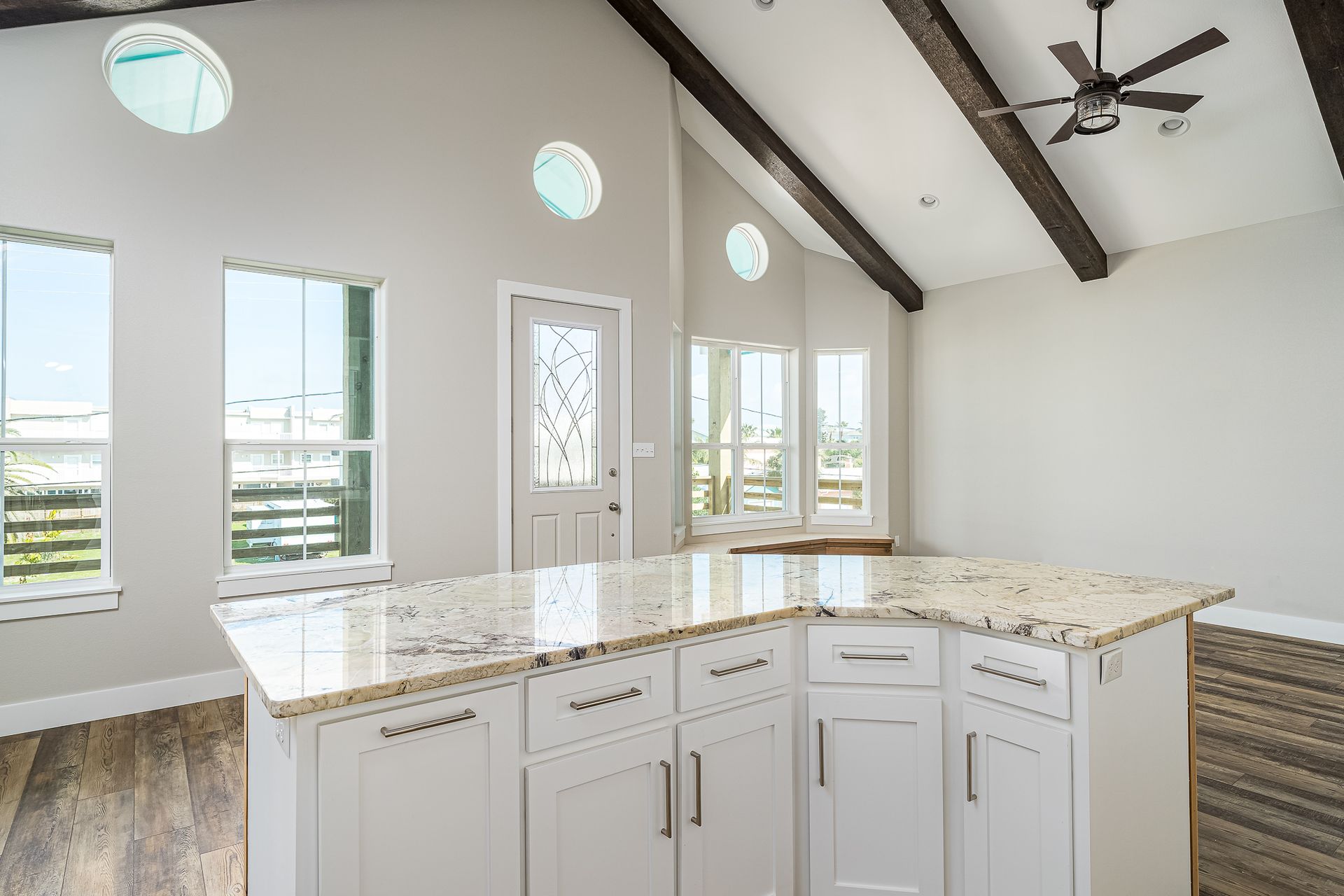 A kitchen with white cabinets and granite counter tops and a ceiling fan.