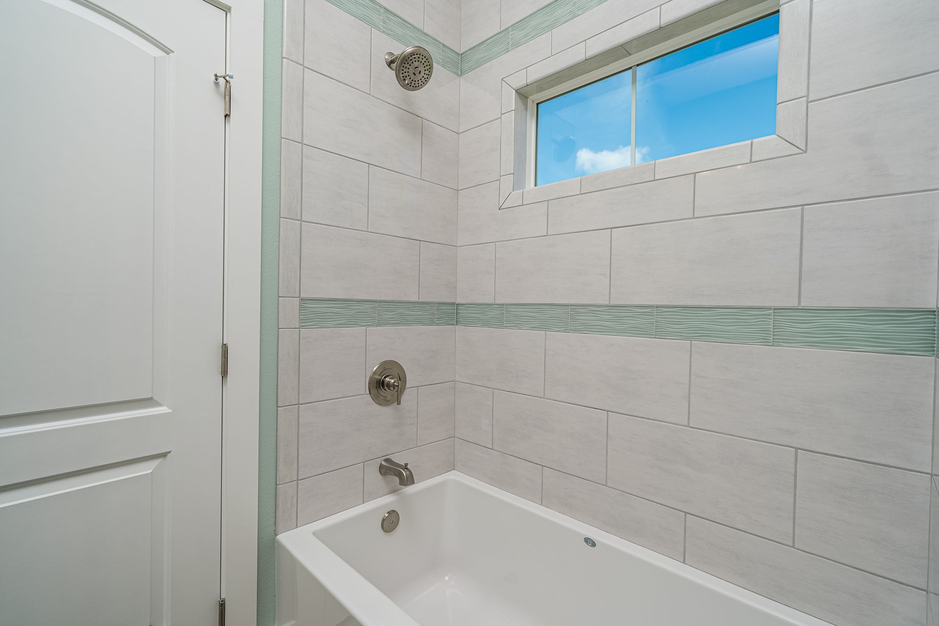 A bathroom with a tub , shower , and window.