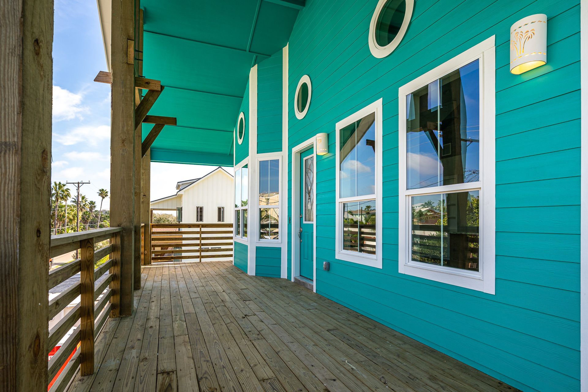 A blue house with a wooden deck and a lot of windows