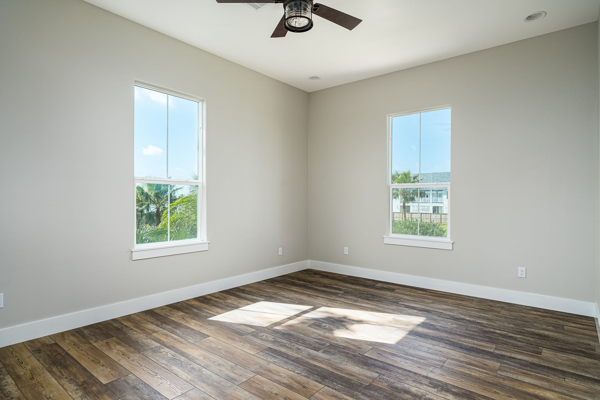 An empty bedroom with hardwood floors and a ceiling fan.