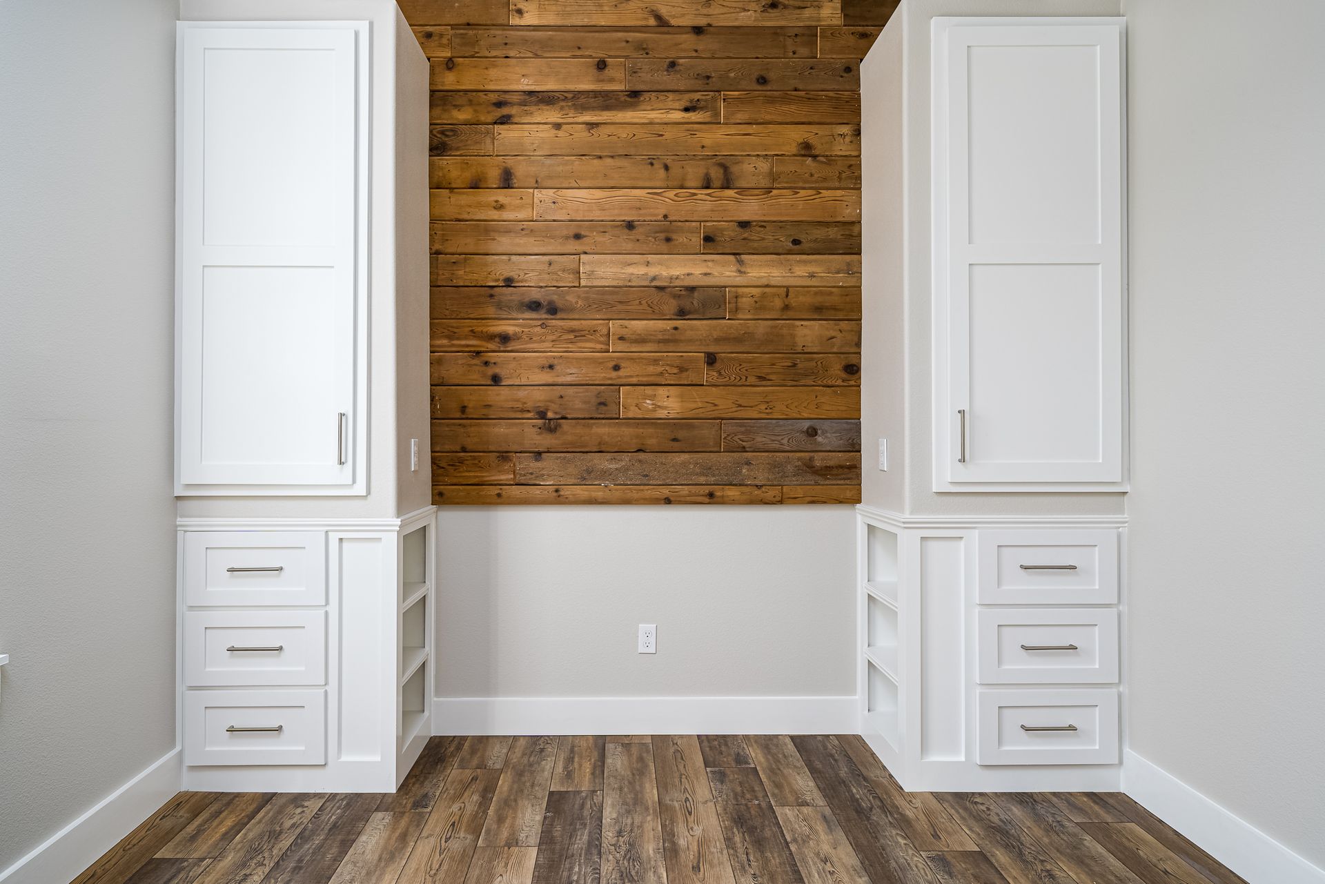 A room with a wooden wall and white cabinets.