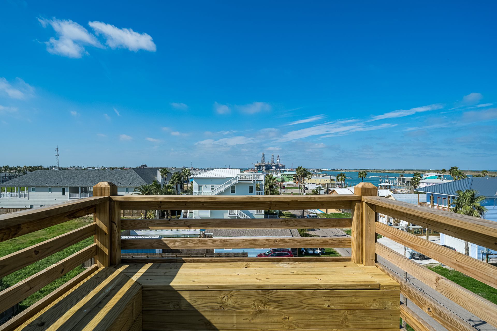 A wooden deck with a view of a city and the ocean.