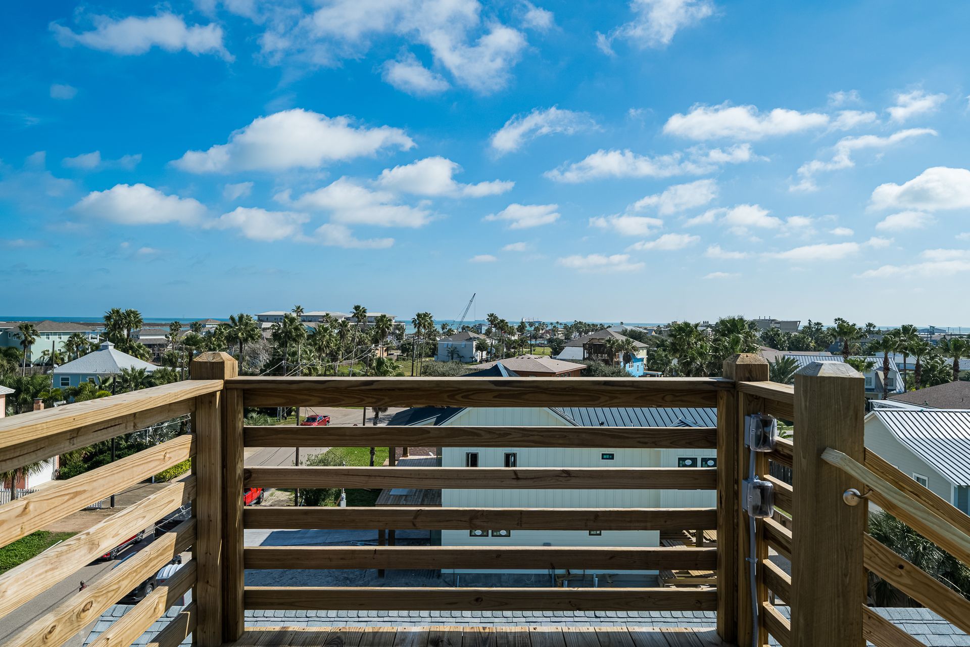 A view of a city from a balcony with a wooden railing.