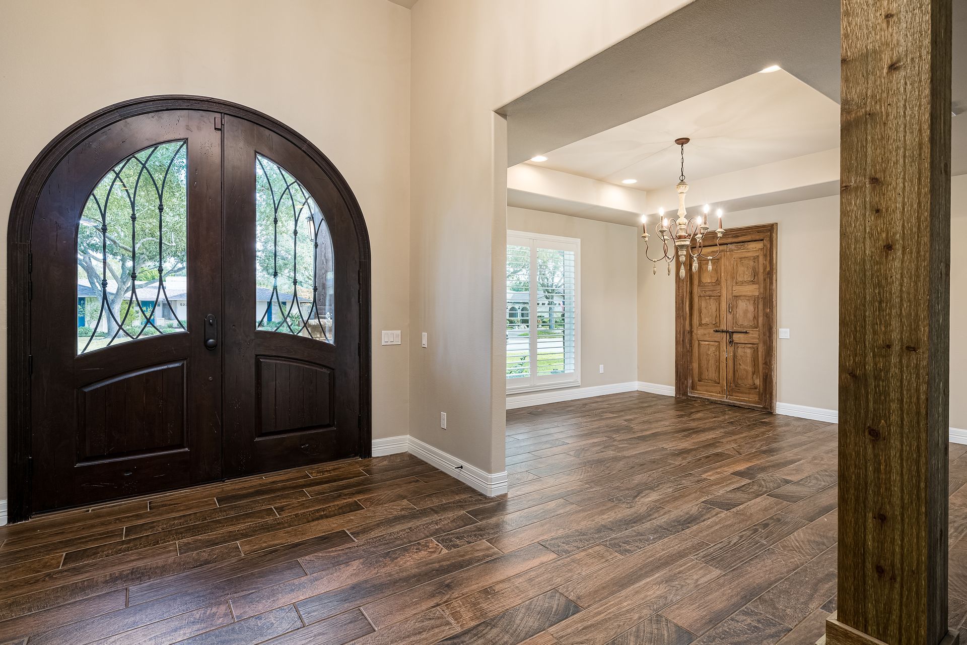 A large empty room with hardwood floors and arched doors.