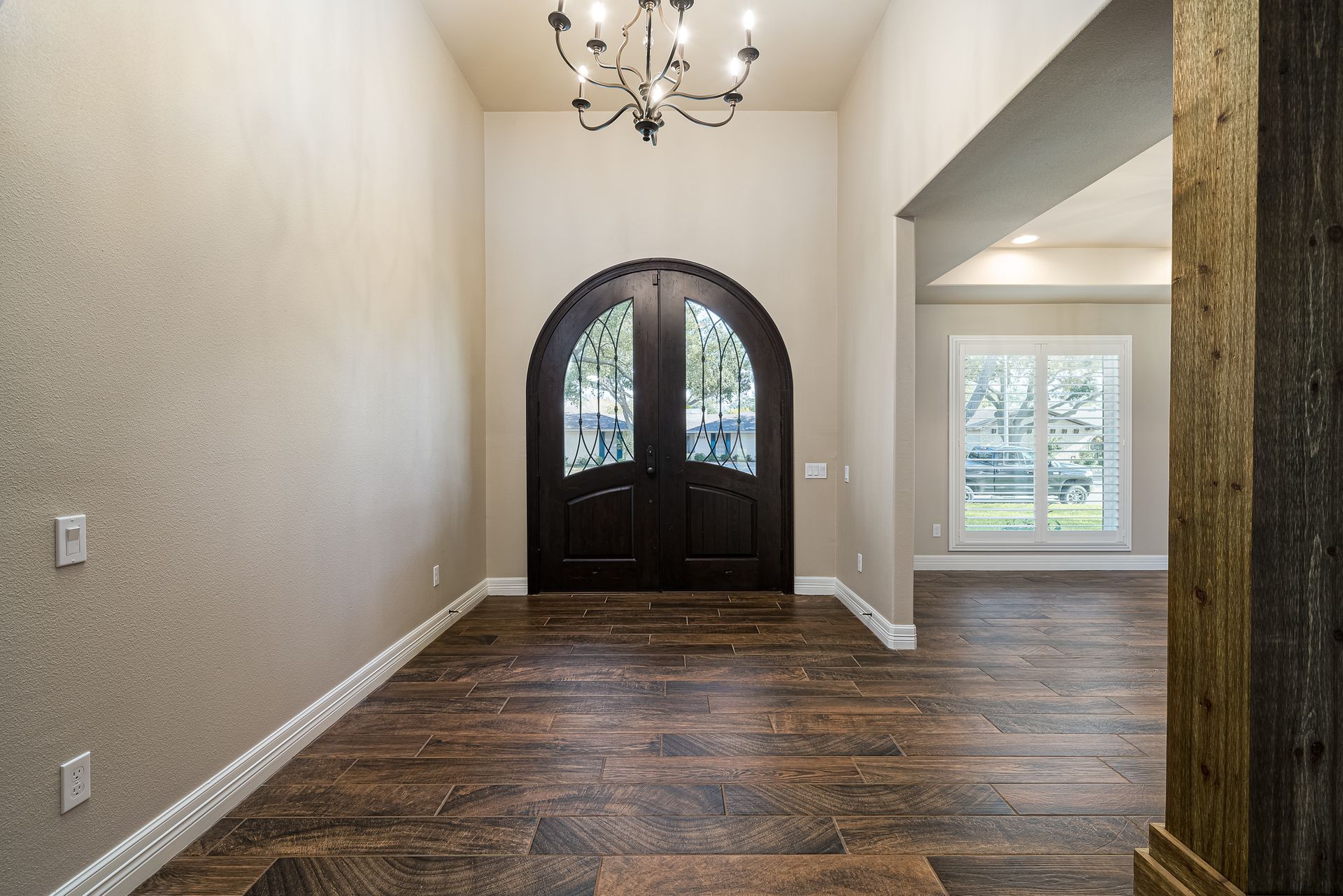 A hallway with a large door and a chandelier hanging from the ceiling.