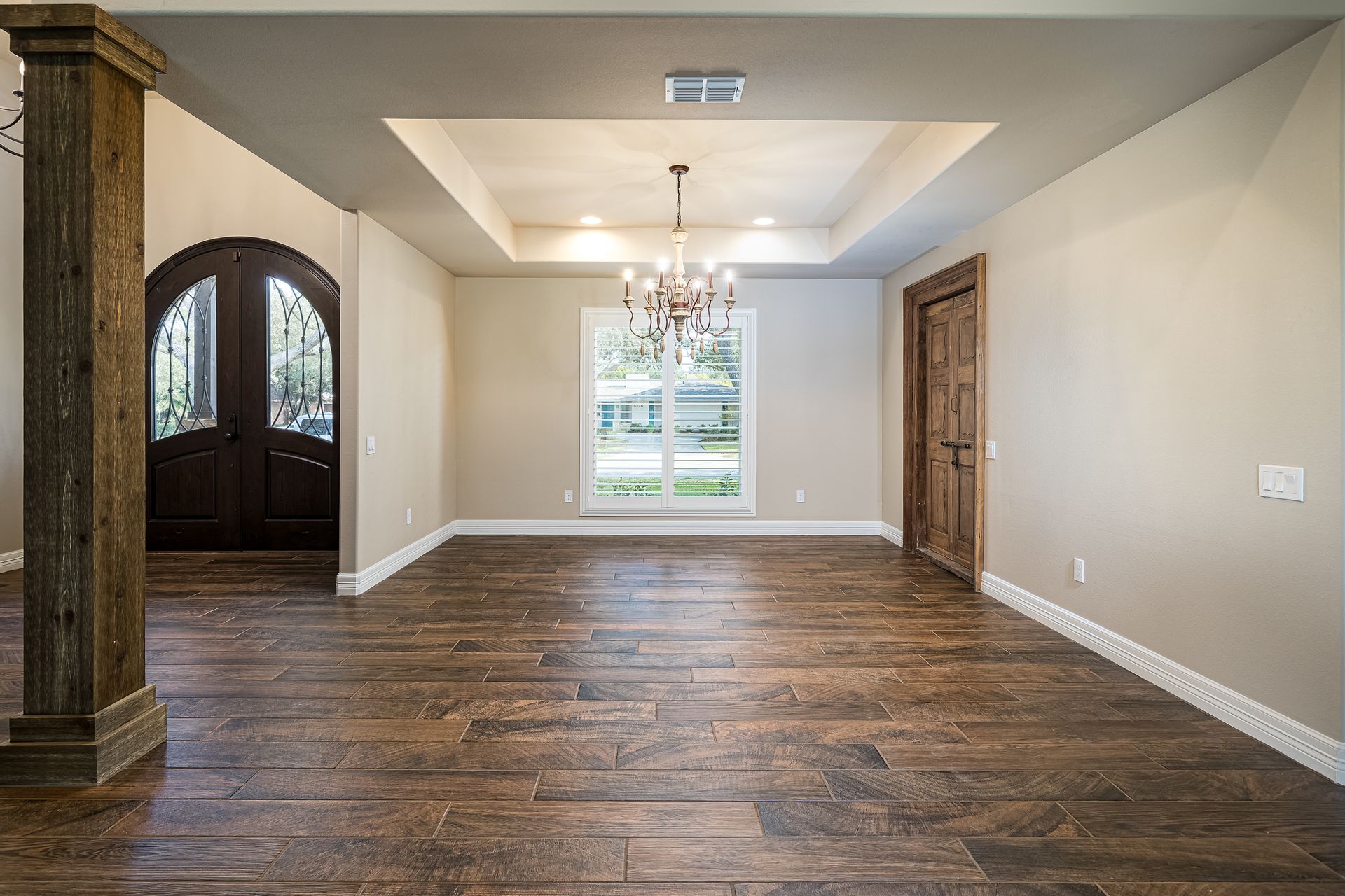 A large empty room with hardwood floors and a chandelier.