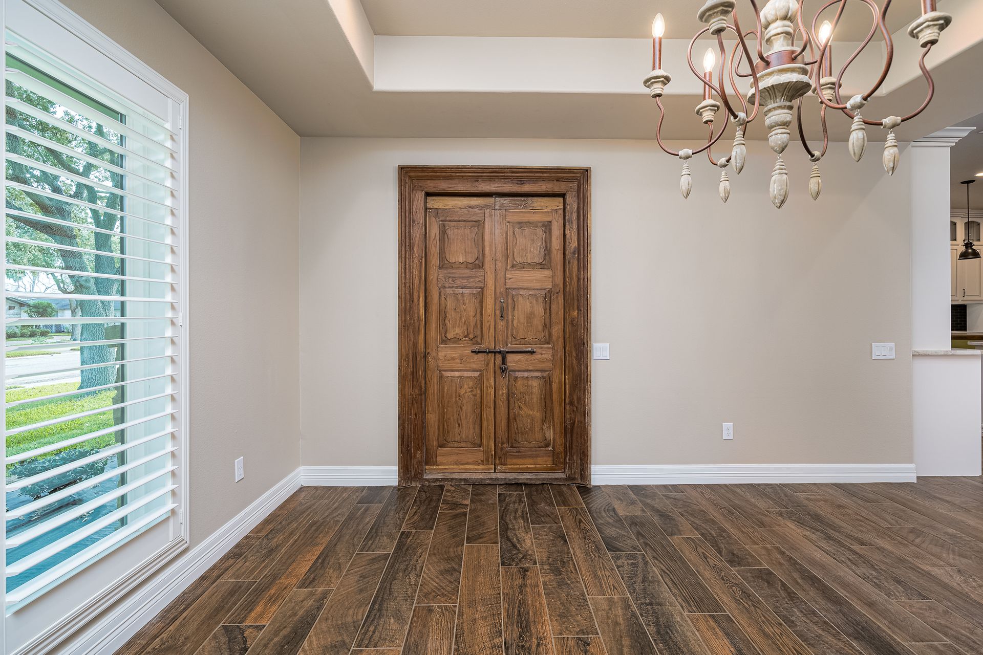 An empty dining room with a wooden floor and a chandelier.