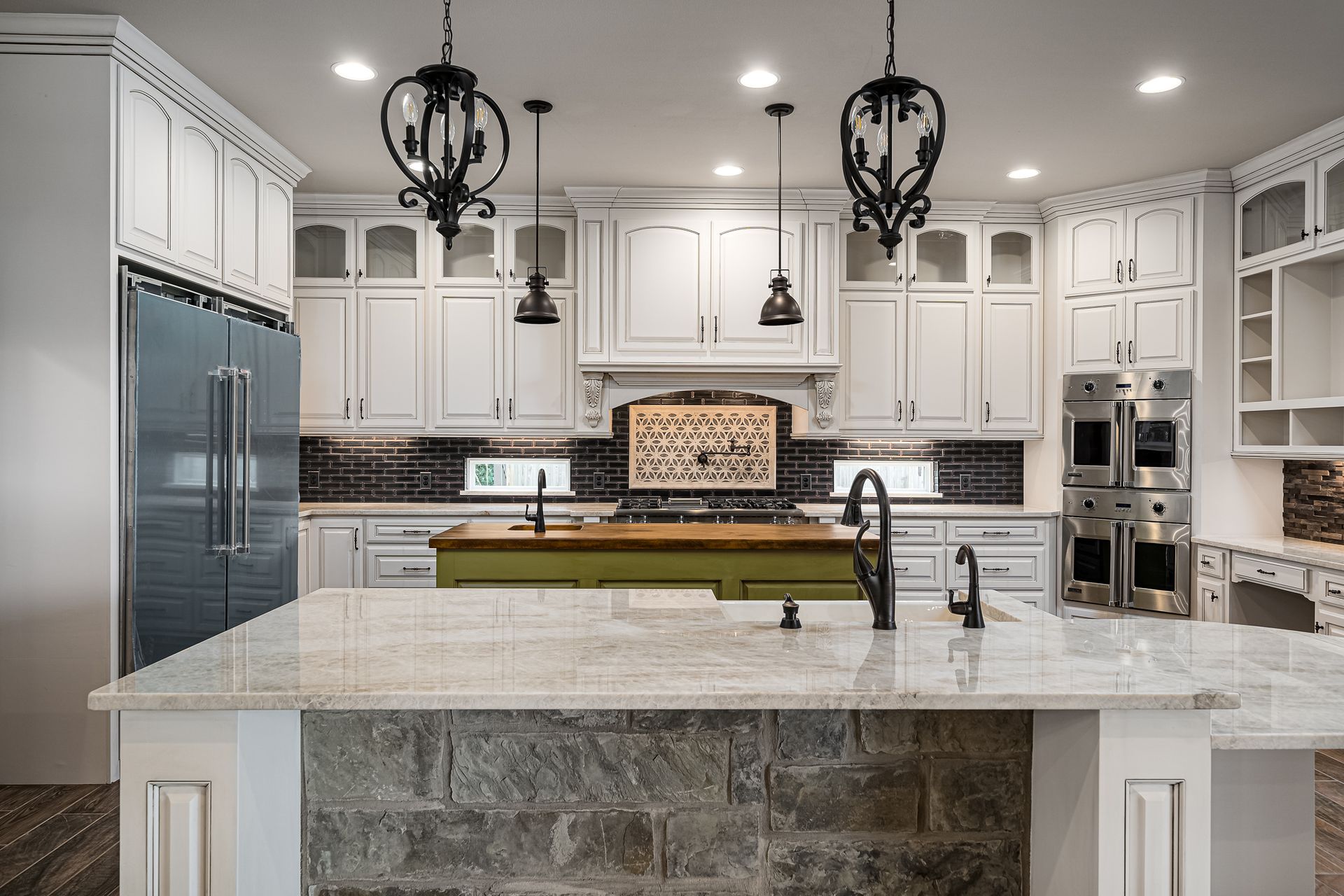 A kitchen with white cabinets , granite counter tops , stainless steel appliances and a large island.