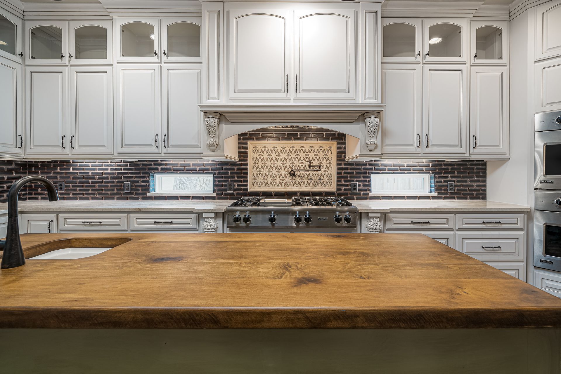 A kitchen with white cabinets and a wooden counter top.