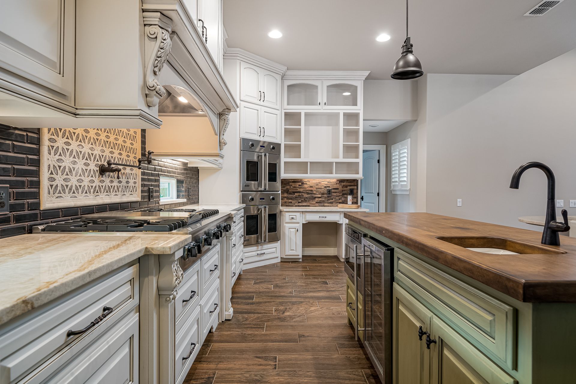 A kitchen with white cabinets , granite counter tops , stainless steel appliances and a large island.