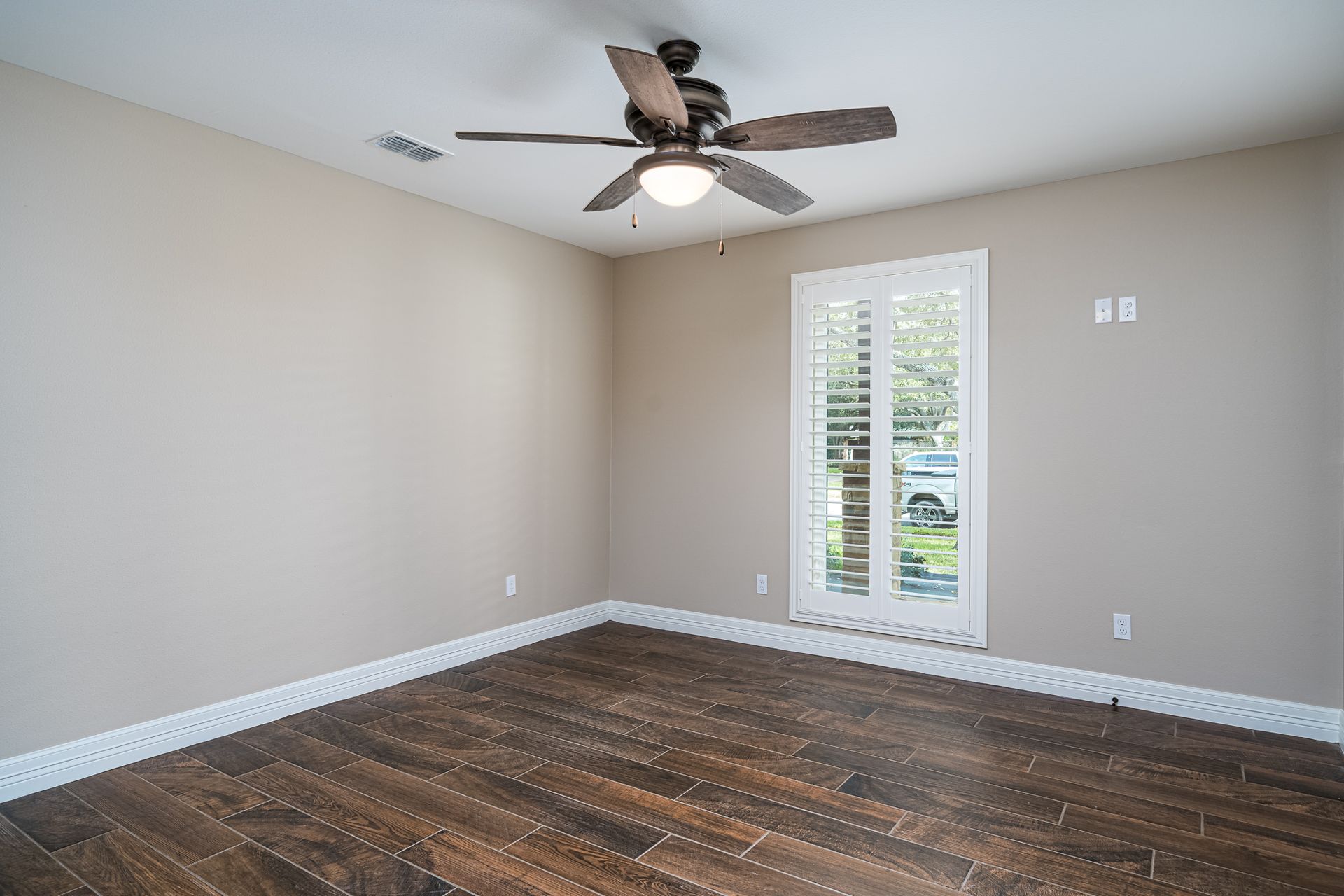 An empty room with a ceiling fan and a window.
