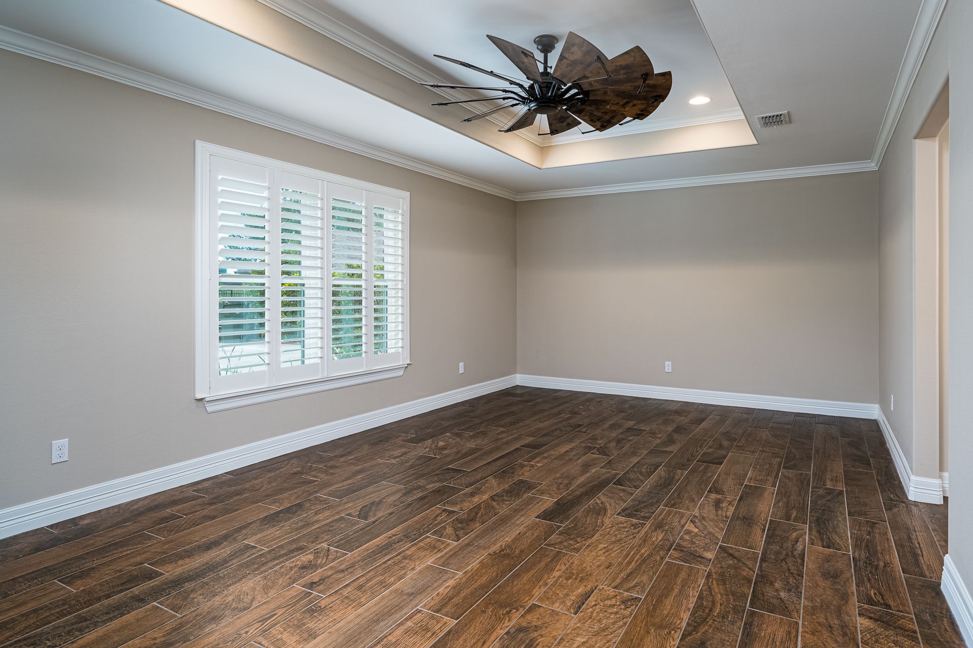 An empty room with hardwood floors and a ceiling fan