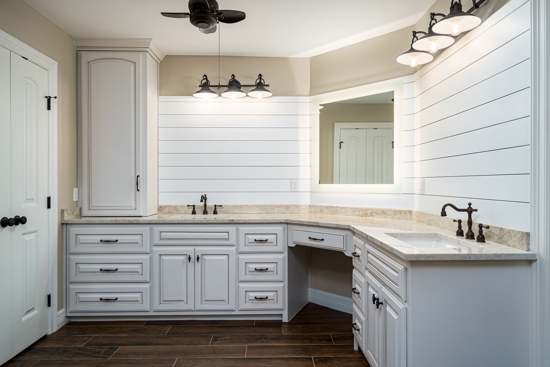 A bathroom with two sinks , a mirror and a ceiling fan.