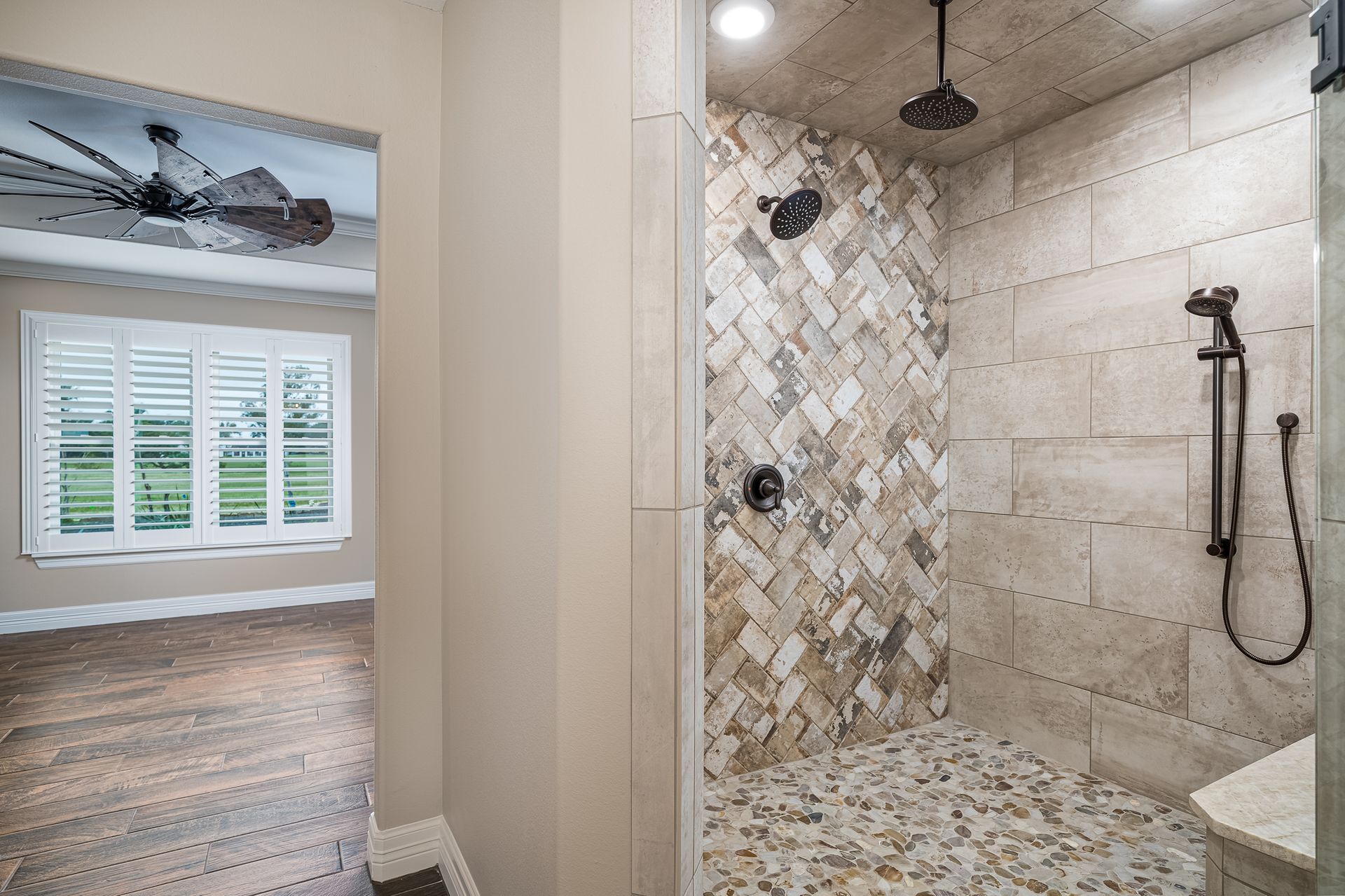 A bathroom with a walk in shower and a ceiling fan.