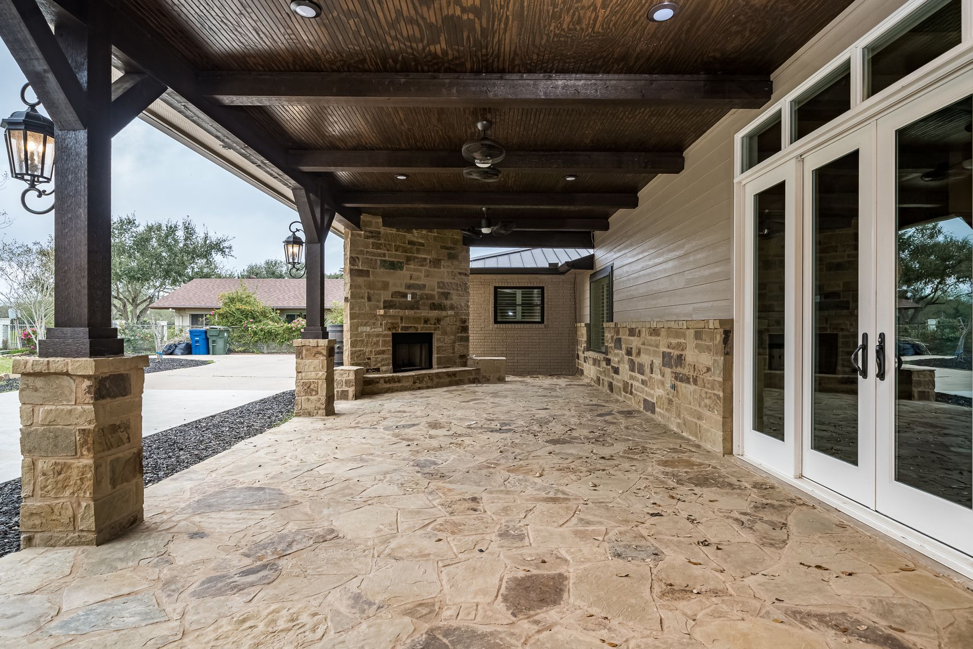 A large covered patio with a fireplace and sliding glass doors.