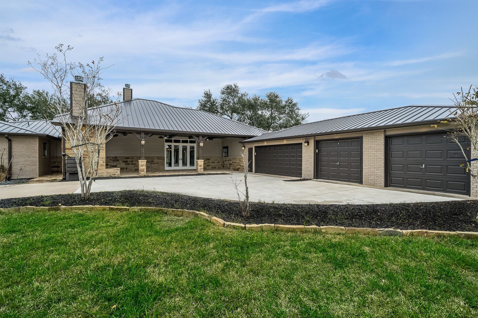A large house with three garages and a large lawn in front of it.