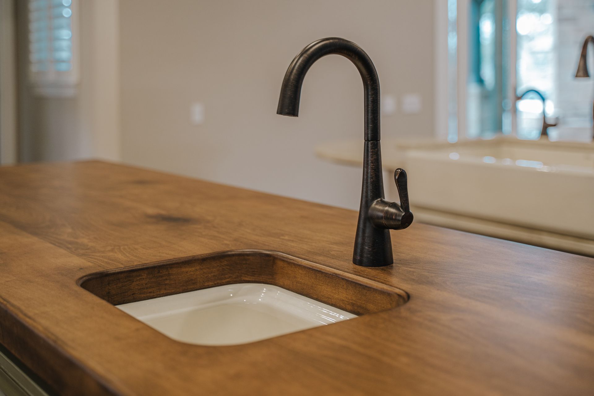 A kitchen sink with a wooden counter top and a black faucet.