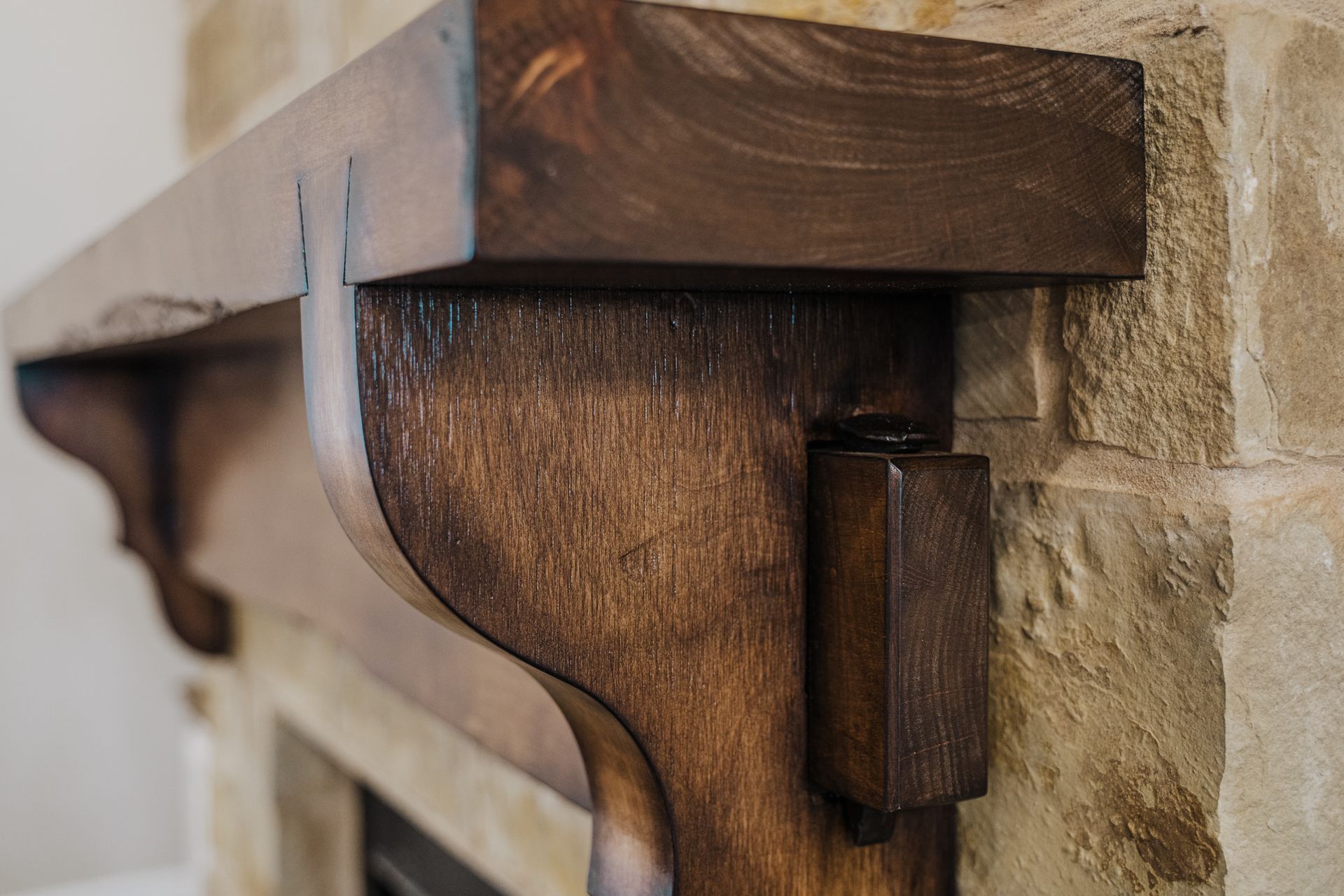 A wooden mantle is attached to a stone fireplace.