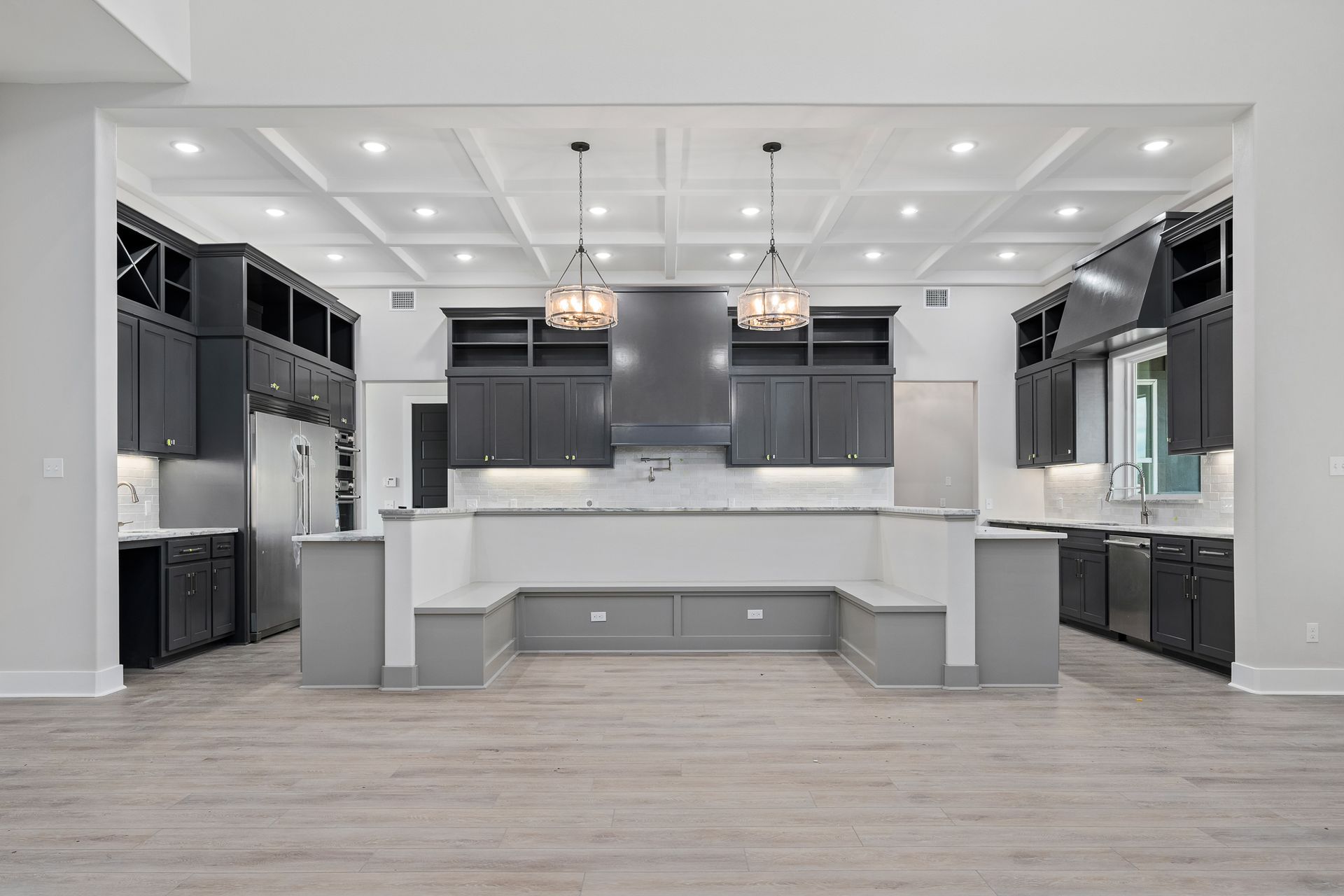 A large empty kitchen with black cabinets and white counter tops.