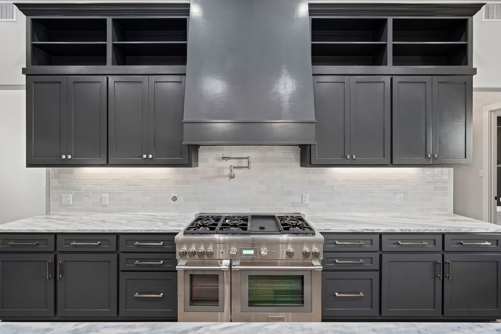 A kitchen with black cabinets and a stove top oven.