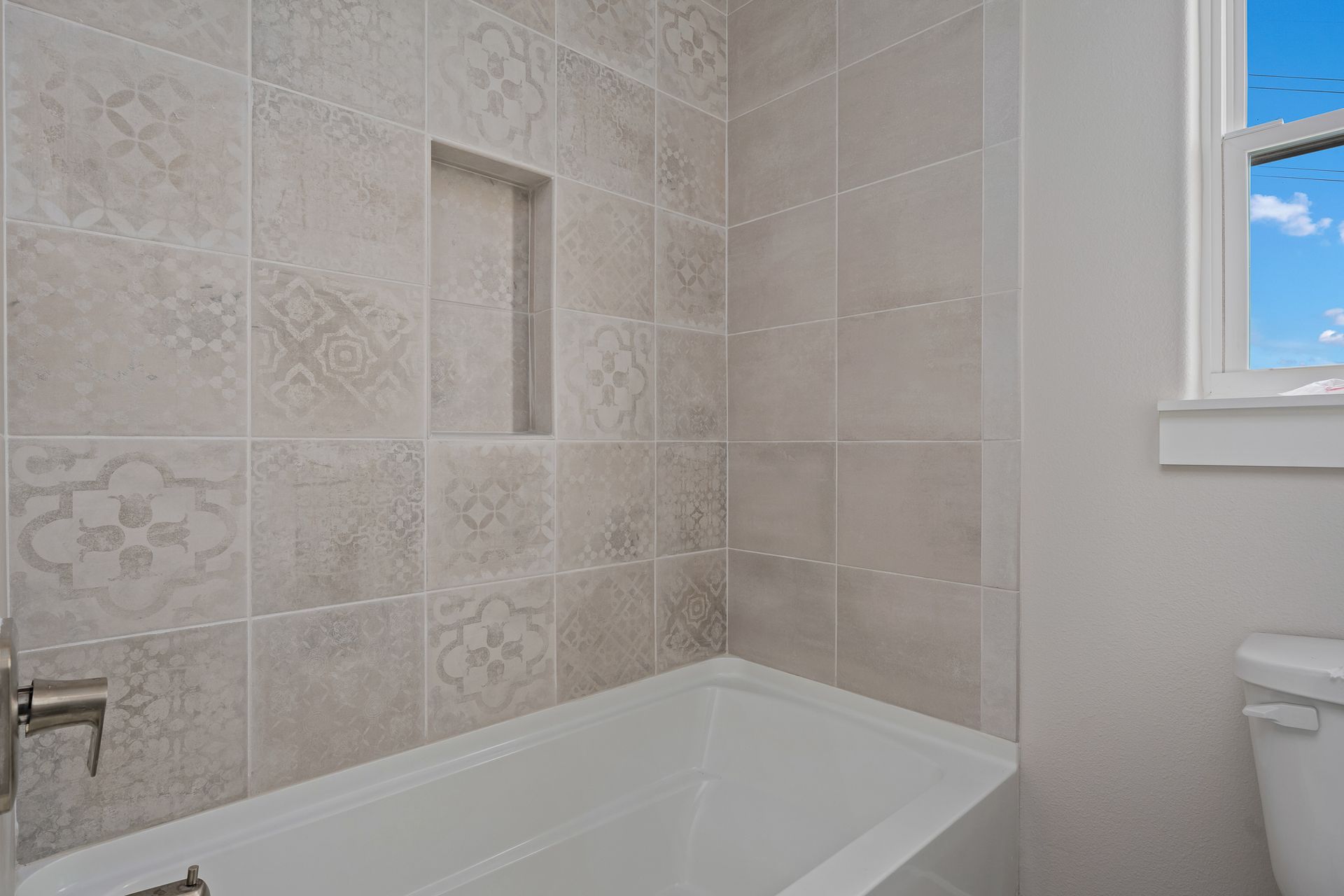 A bathroom with a bathtub , toilet and window.